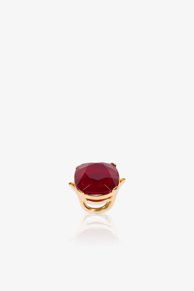 A Ruby Faceted Cocktail Ring featuring a large, faceted deep red gemstone set in a prong setting is displayed on a white background with a subtle reflection beneath it.