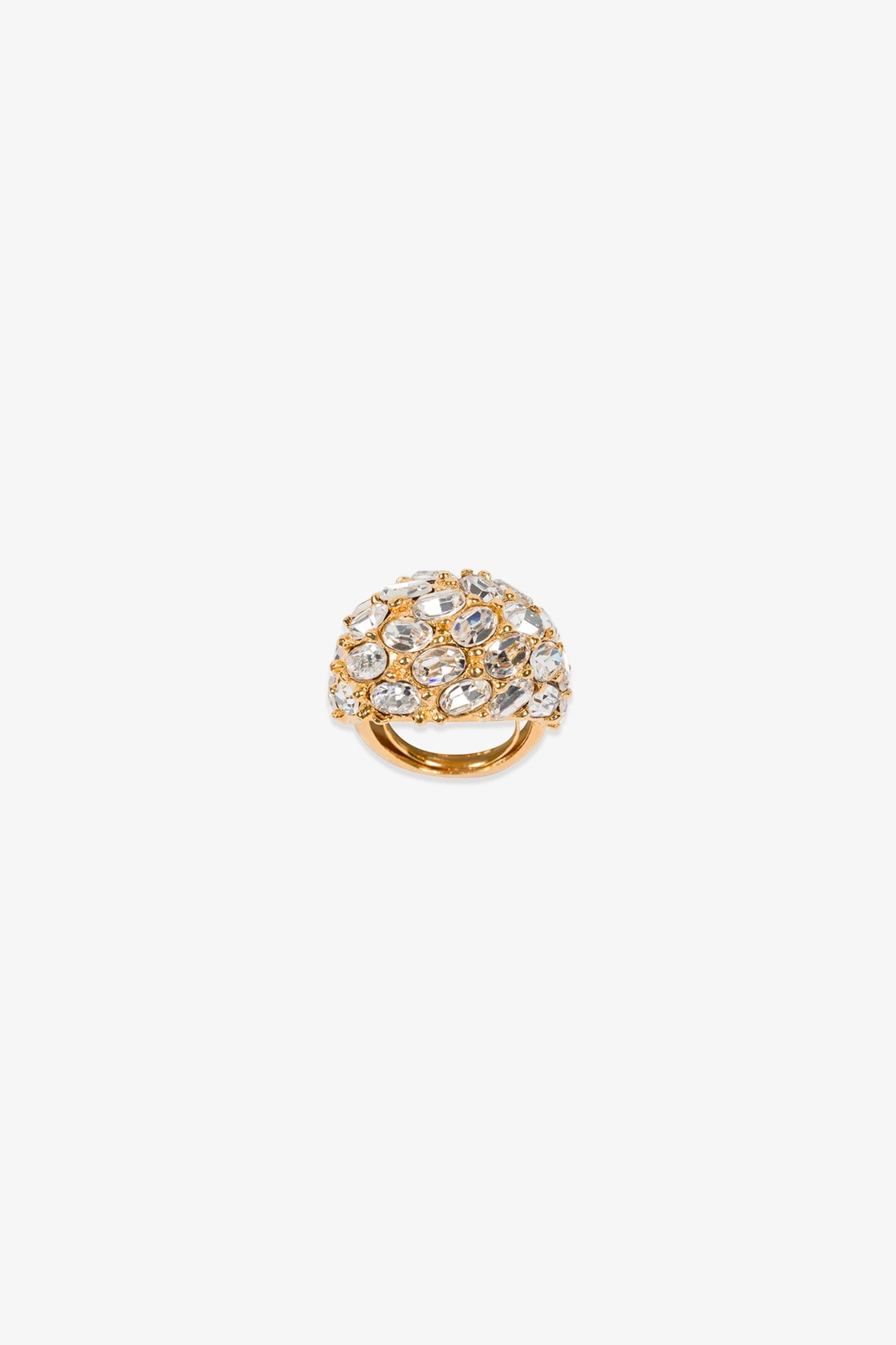 The Cluster Stone Dome Ring features a domed gold design adorned with clear gemstones of varying sizes, and is displayed on a plain white background.