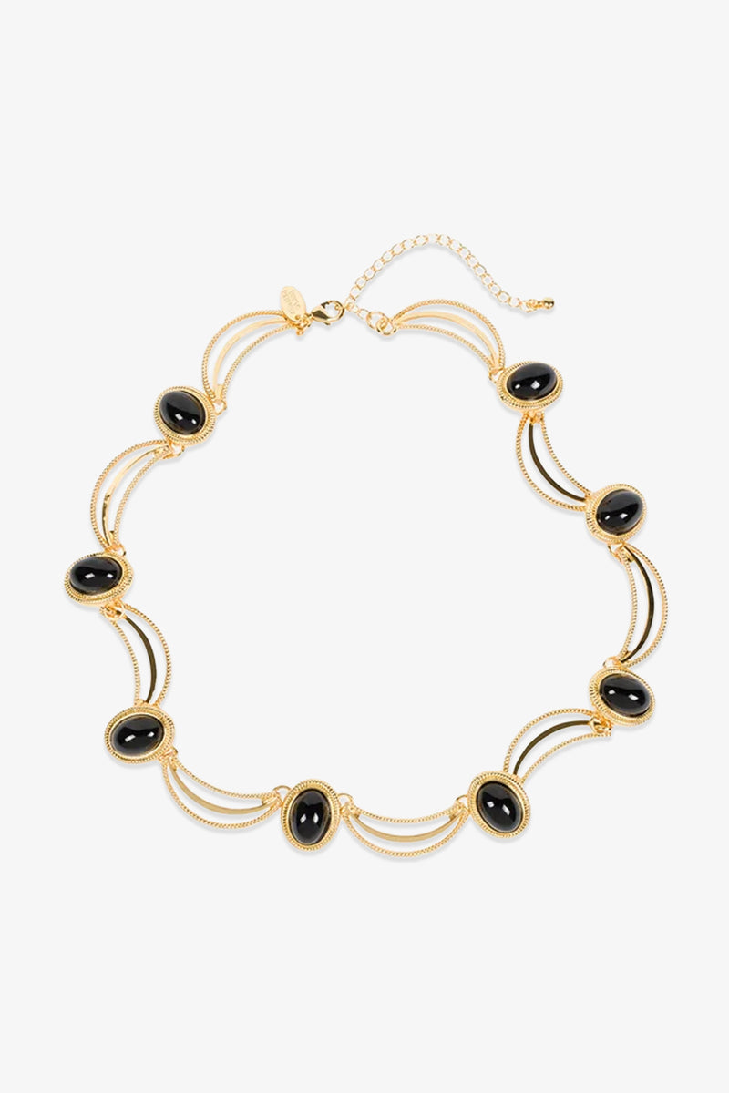 Introducing the Oval Jet Scallop Necklace: a gold necklace featuring evenly spaced black oval stones, each cradled in a gold frame and linked by delicate, curved gold strands. Finished with an adjustable clasp at the top for a perfect fit.