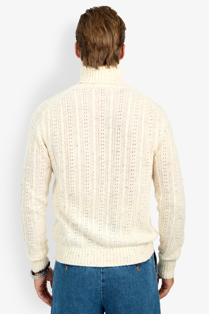 A person shown from the back wears the cream-colored Wesley Turtleneck Sweater and blue jeans against a plain white background.