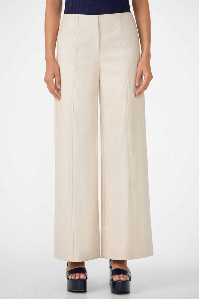 A person models the Parque Pant, a high-waisted, wide-leg cream-colored style. Only their lower torso and legs are shown as they stand against a plain white background in black platform heels.