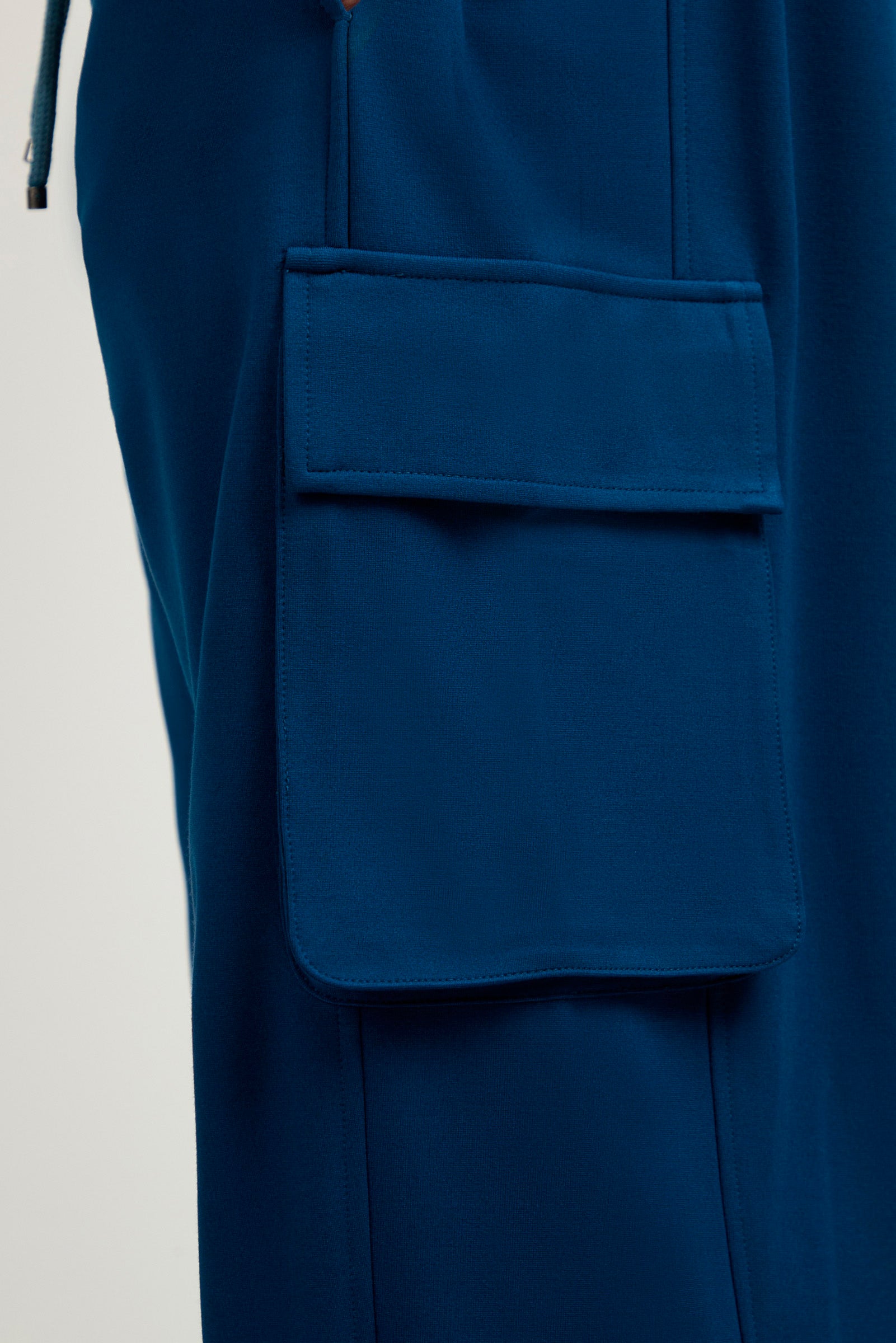 Close-up of the Lounge Cargo Pant in blue, showcasing a large rectangular side cargo pocket with a flap.