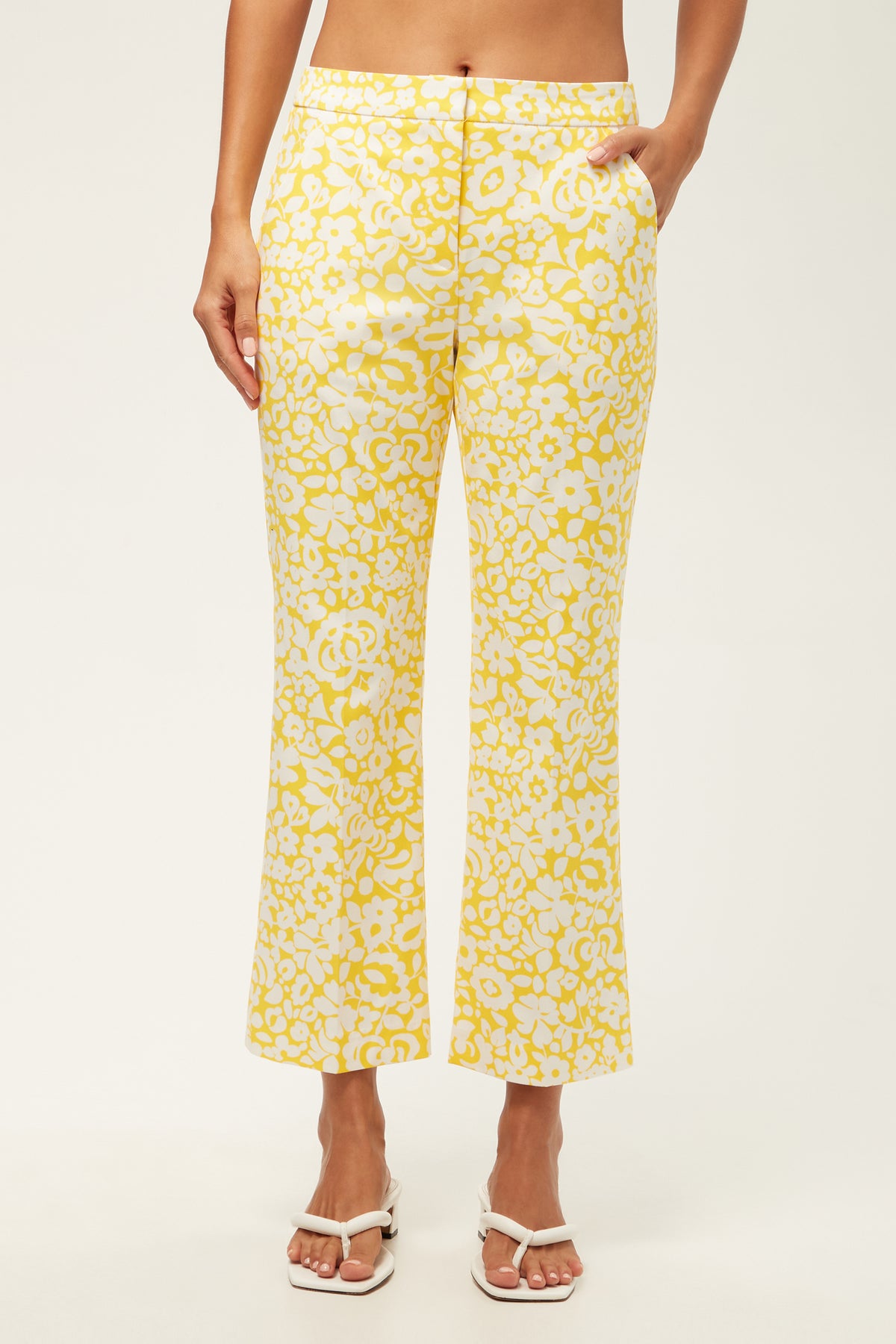 Wearing the Lulu Cropped Pant - Poolside Gossip in Desert Sun, a person stands with hands in pockets, paired with white sandals against a plain background.