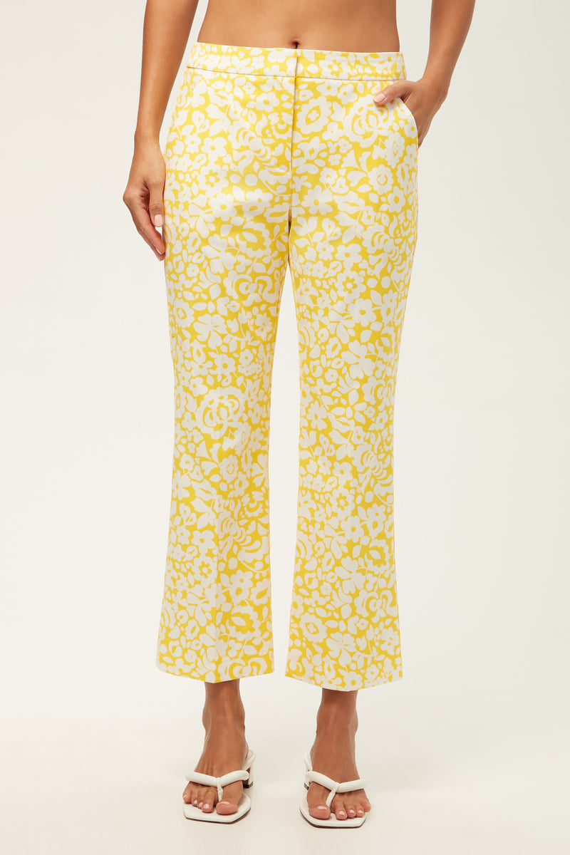 Wearing the Lulu Cropped Pant - Poolside Gossip in Desert Sun, a person stands with hands in pockets, paired with white sandals against a plain background.