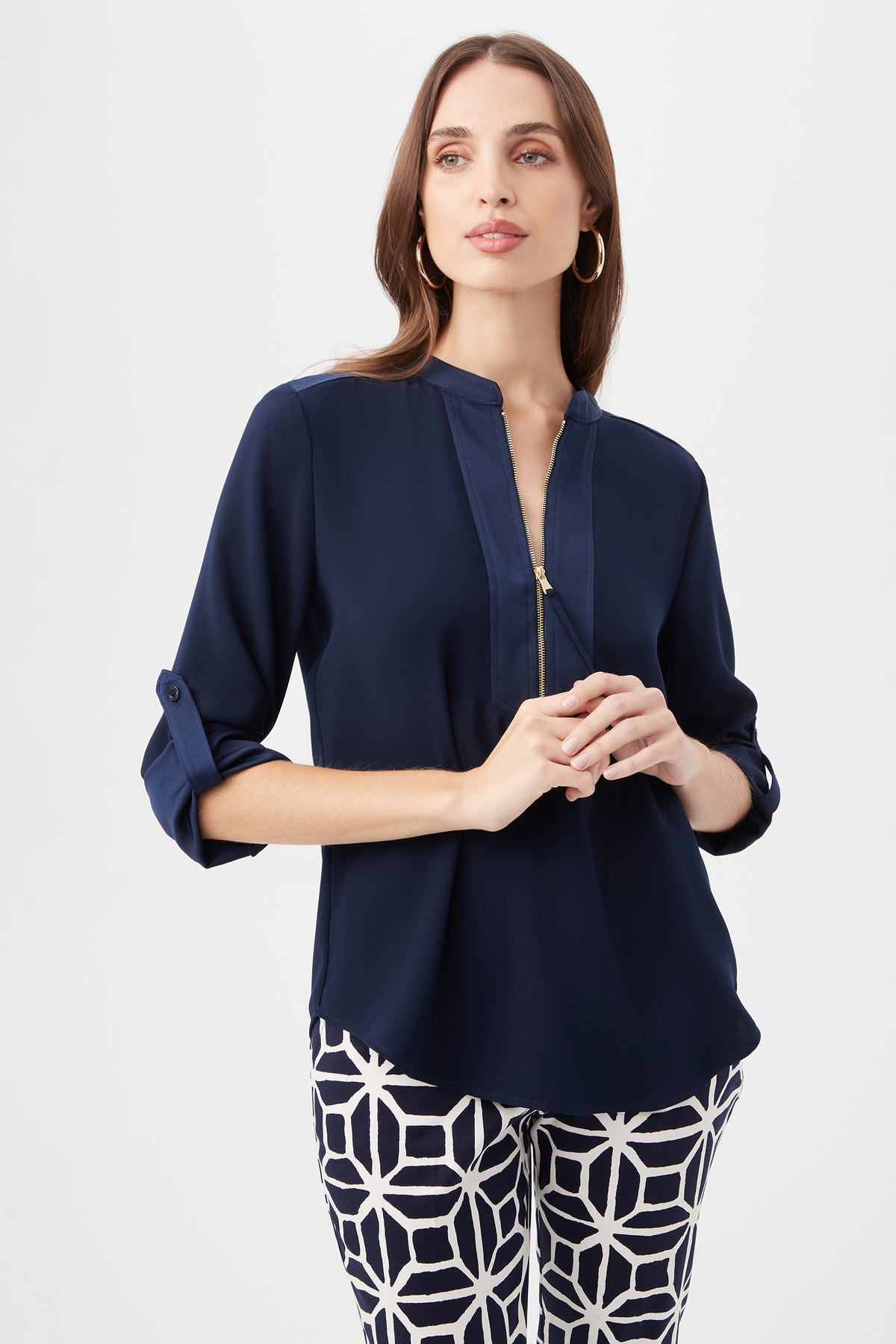 A woman with long brown hair stands against a plain white background wearing the Kaiko 3/4-Sleeve Half-Zip Top in indigo and patterned black-and-white pants, looking slightly to the side.