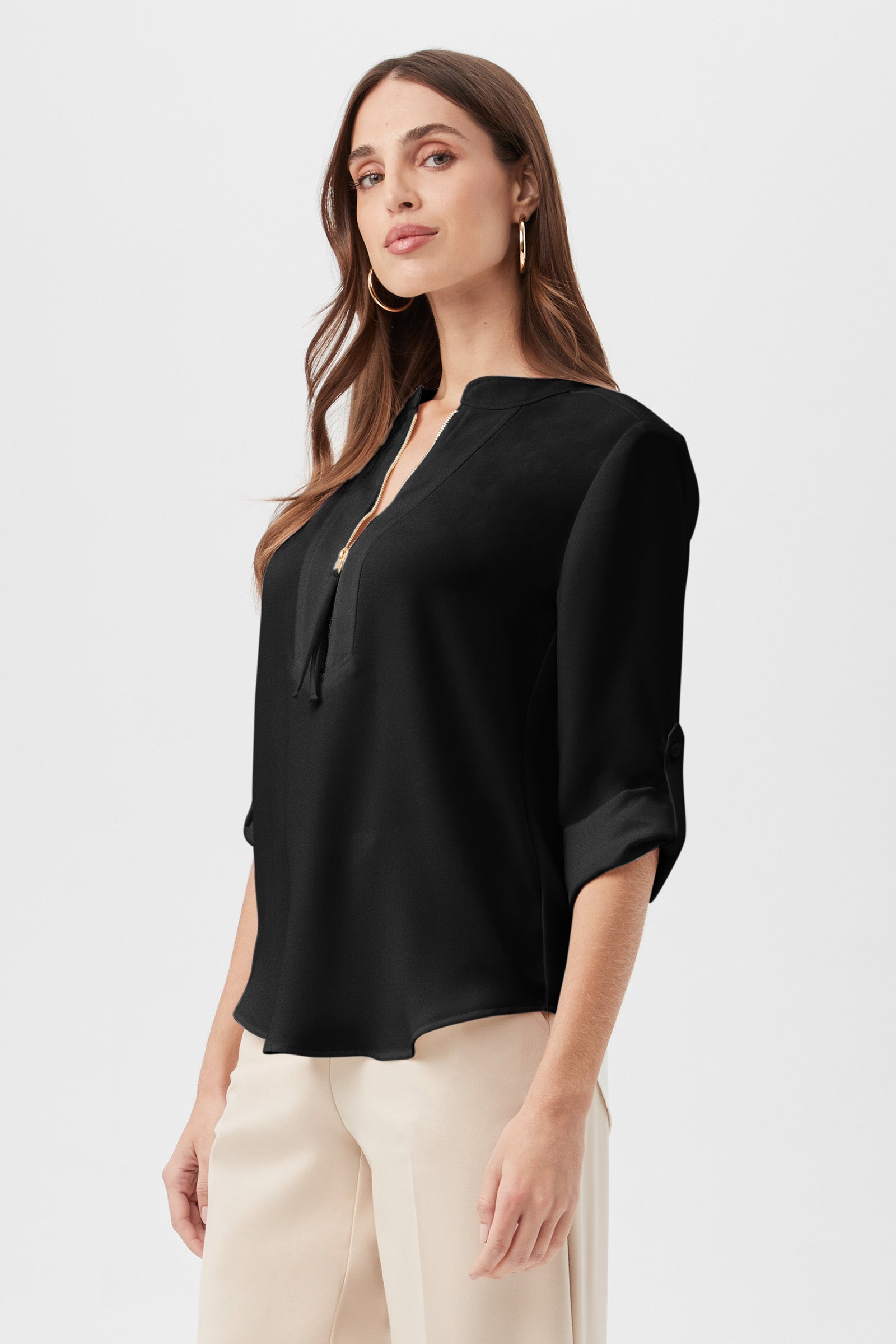 A woman with long brown hair wears the Kaiko 3/4-Sleeve Half-Zip Top in black with beige pants, standing against a plain white background.