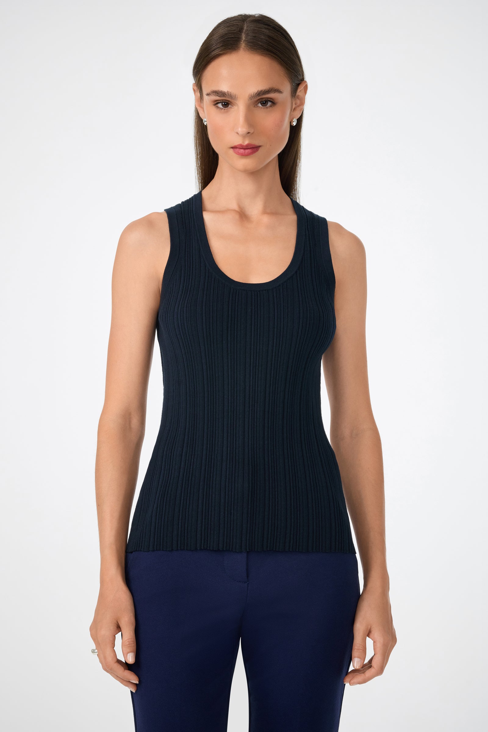 A woman with straight brown hair wears the sleeveless, ribbed Gibraltar Tank in navy with matching pants, standing facing forward against a plain white background.