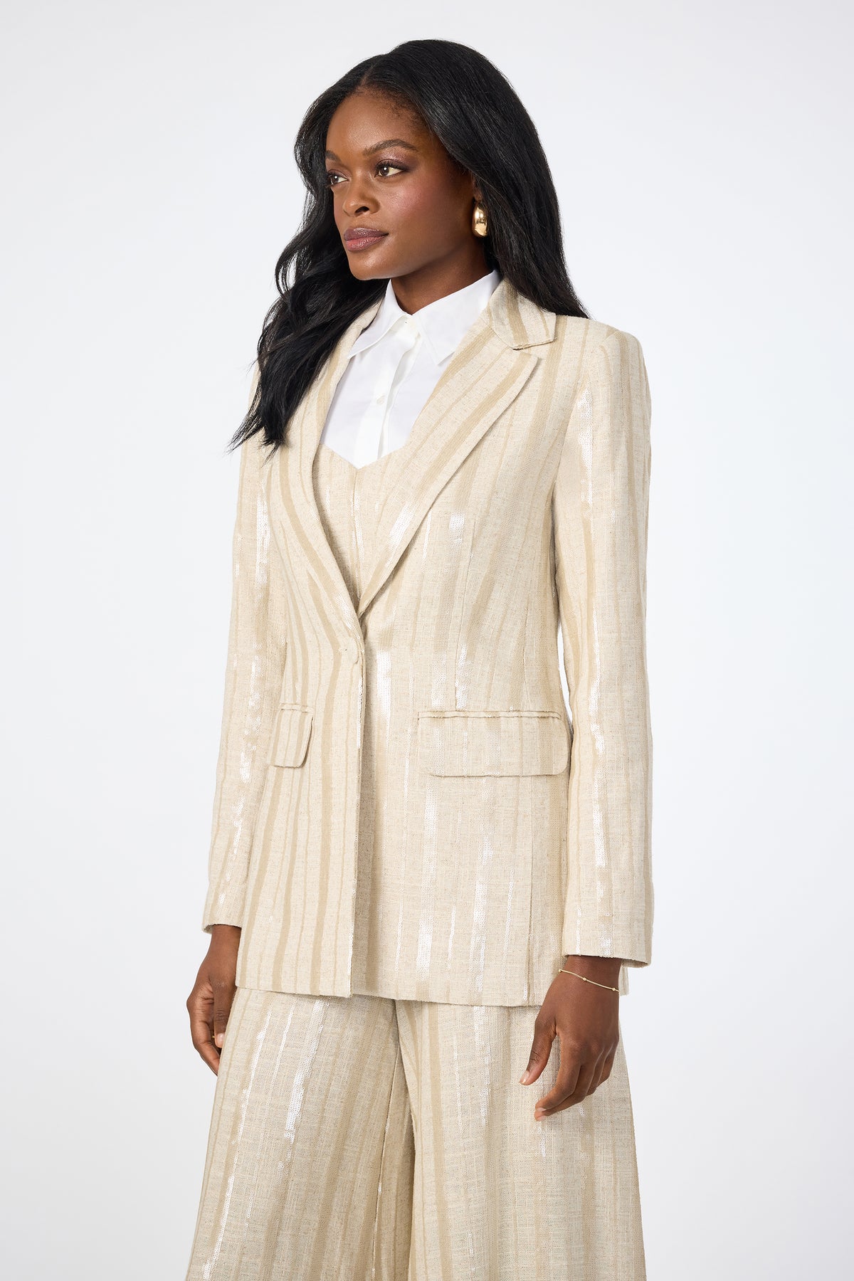 A woman with long black hair wears the Alternates 2 Blazer and matching wide-leg pants over a white collared shirt. She stands against a plain white background, gazing slightly to the side.