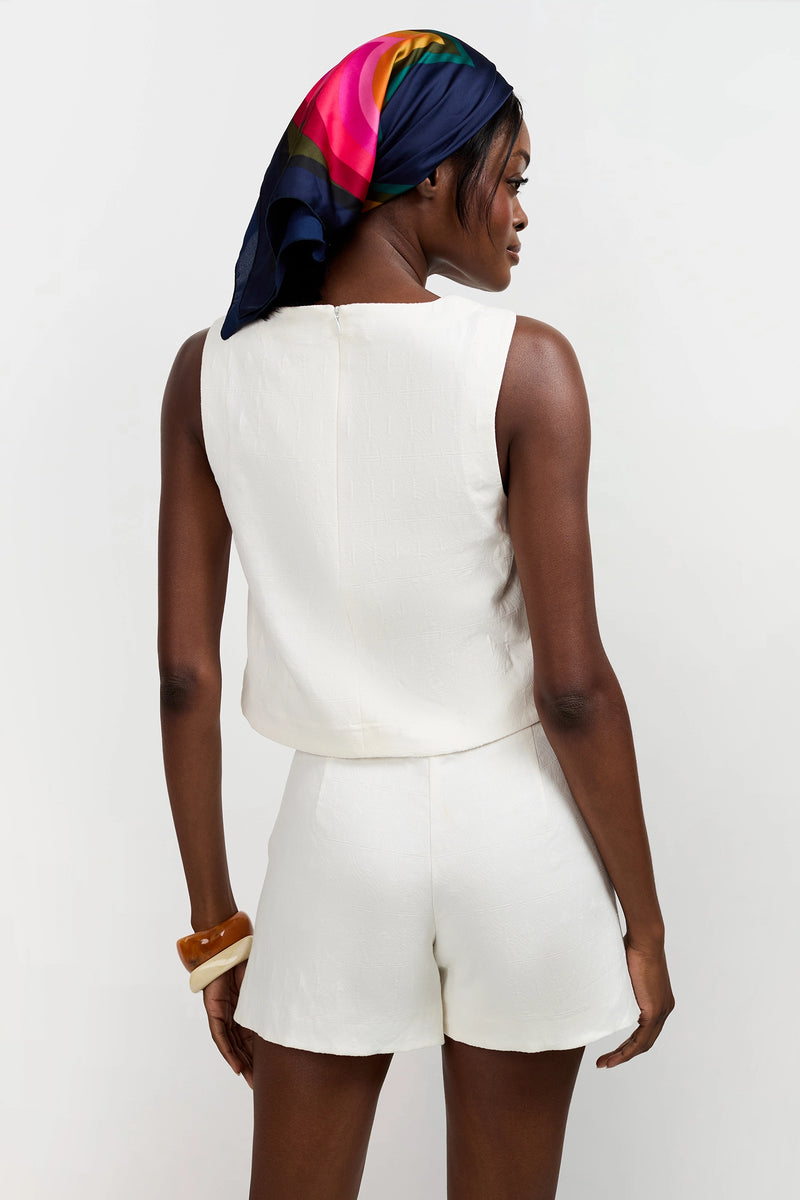 A woman stands with her back to the camera in a Siara Button Side Top and matching shorts, accessorized with a colorful silk scarf and chunky bangles. The background is plain white.