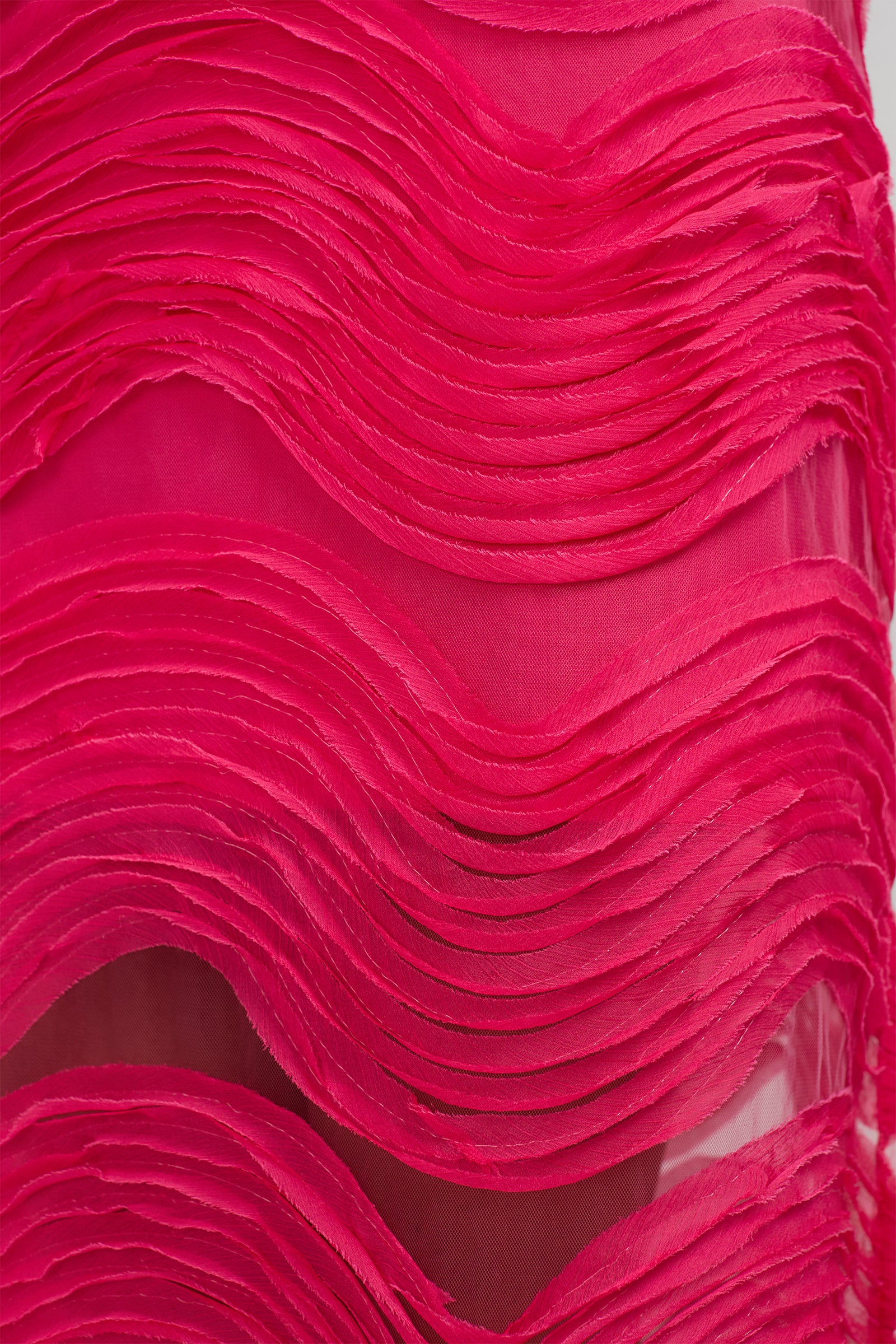 Close-up of the Belisama Organza Midi Dress, showcasing its bright pink, wavy layered strips on a semi-sheer background that adds movement and depth to the textured fabric.