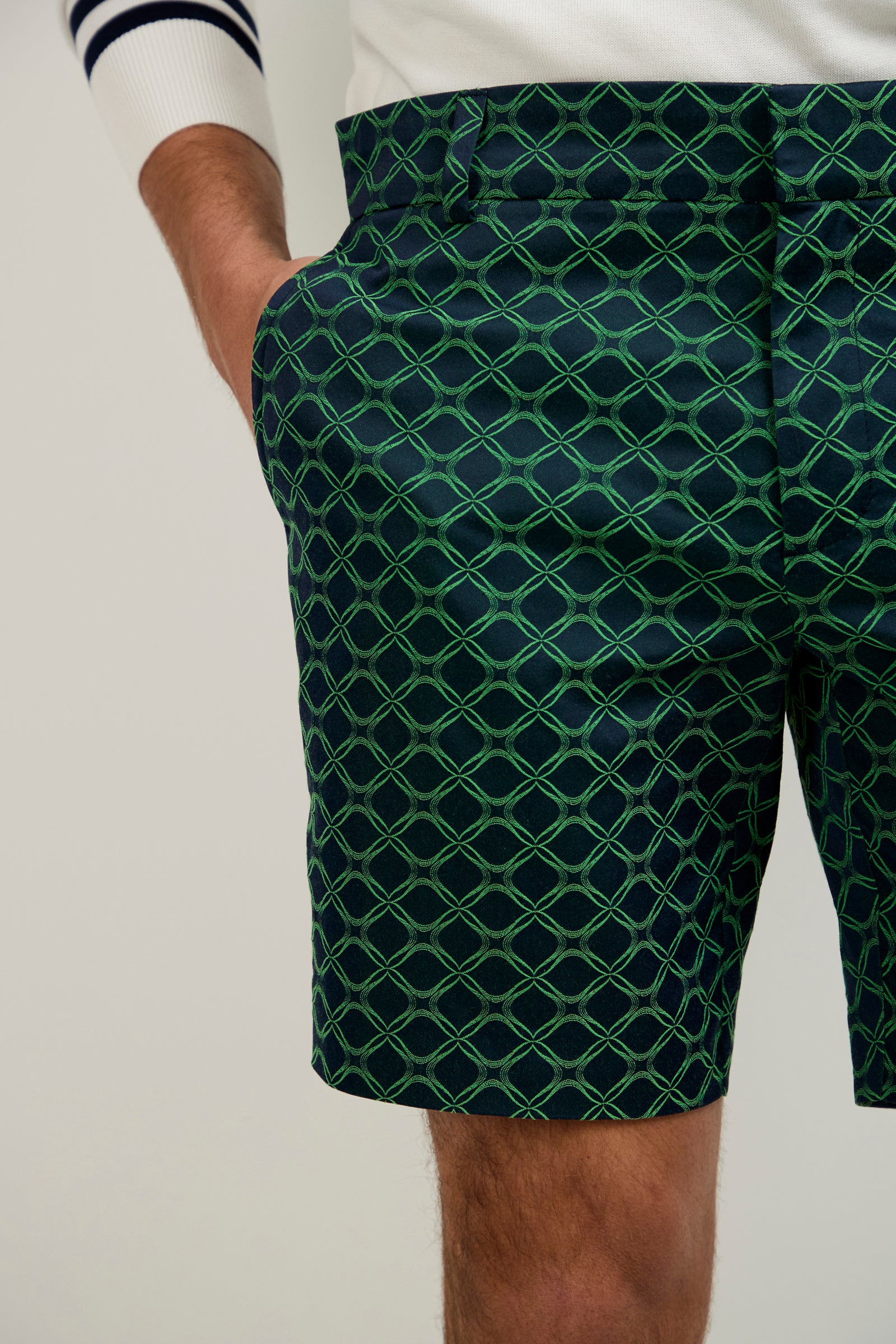 Someone wearing the Lawrence Short in Clover Geo Jacquard with a white sweater featuring a navy striped cuff and their left hand in their pocket.