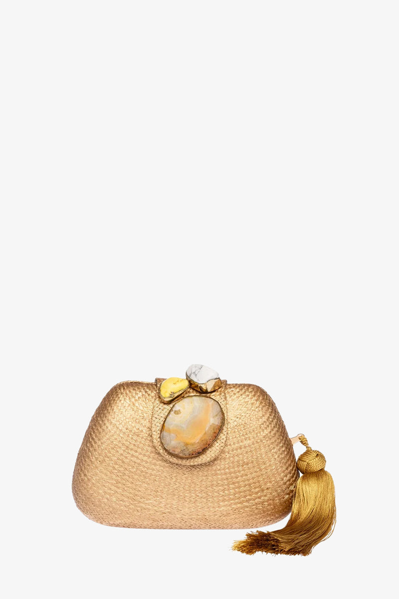 The Tamu Bean Clutch is a small GOLD woven purse featuring a large stone clasp and a decorative gold tassel on one side, displayed against a plain white background.