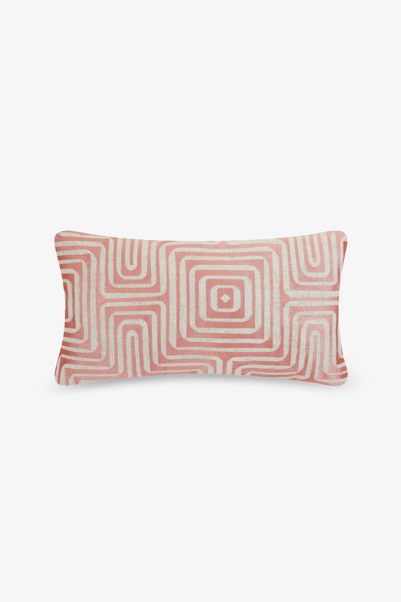 The Amazing Maze Embroidered Lumbar Pillow features a geometric pattern of concentric squares in shades of pink and white, set against a plain white background.