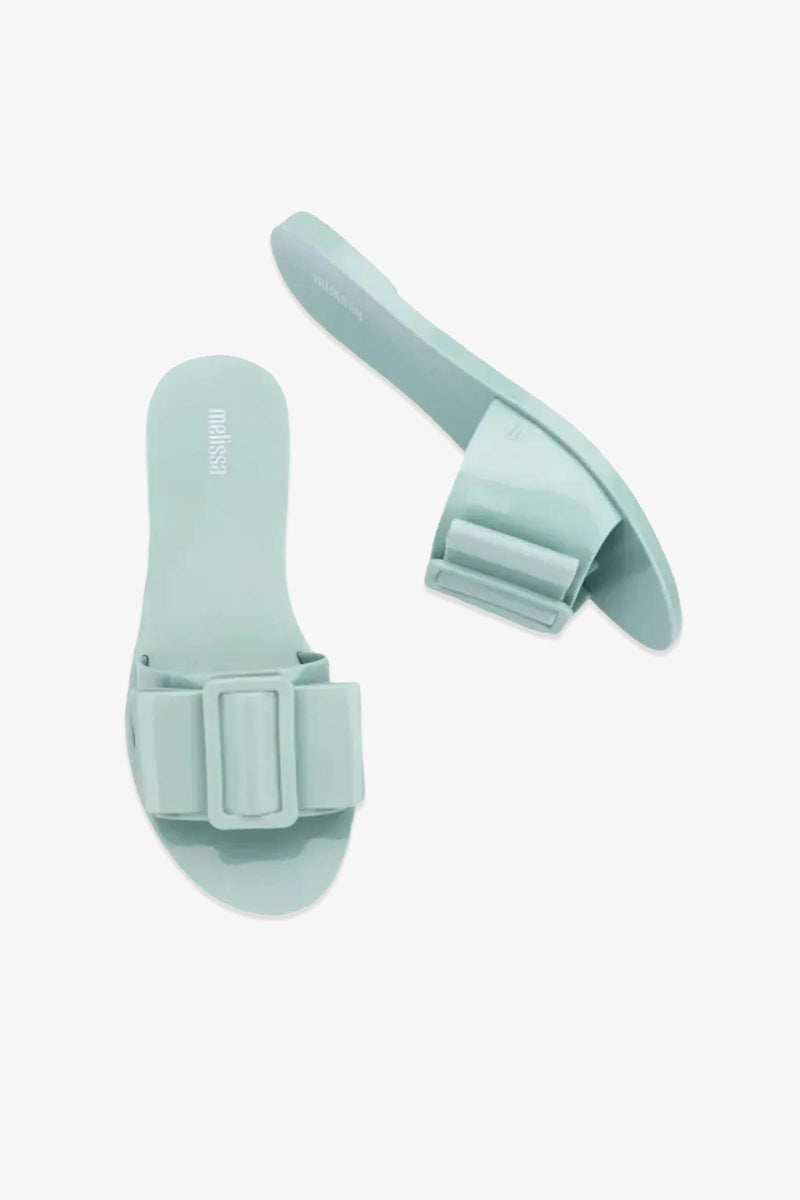 Two mint green Babe Sandals with wide straps featuring large, rectangular decorative bows, displayed on a plain white background.