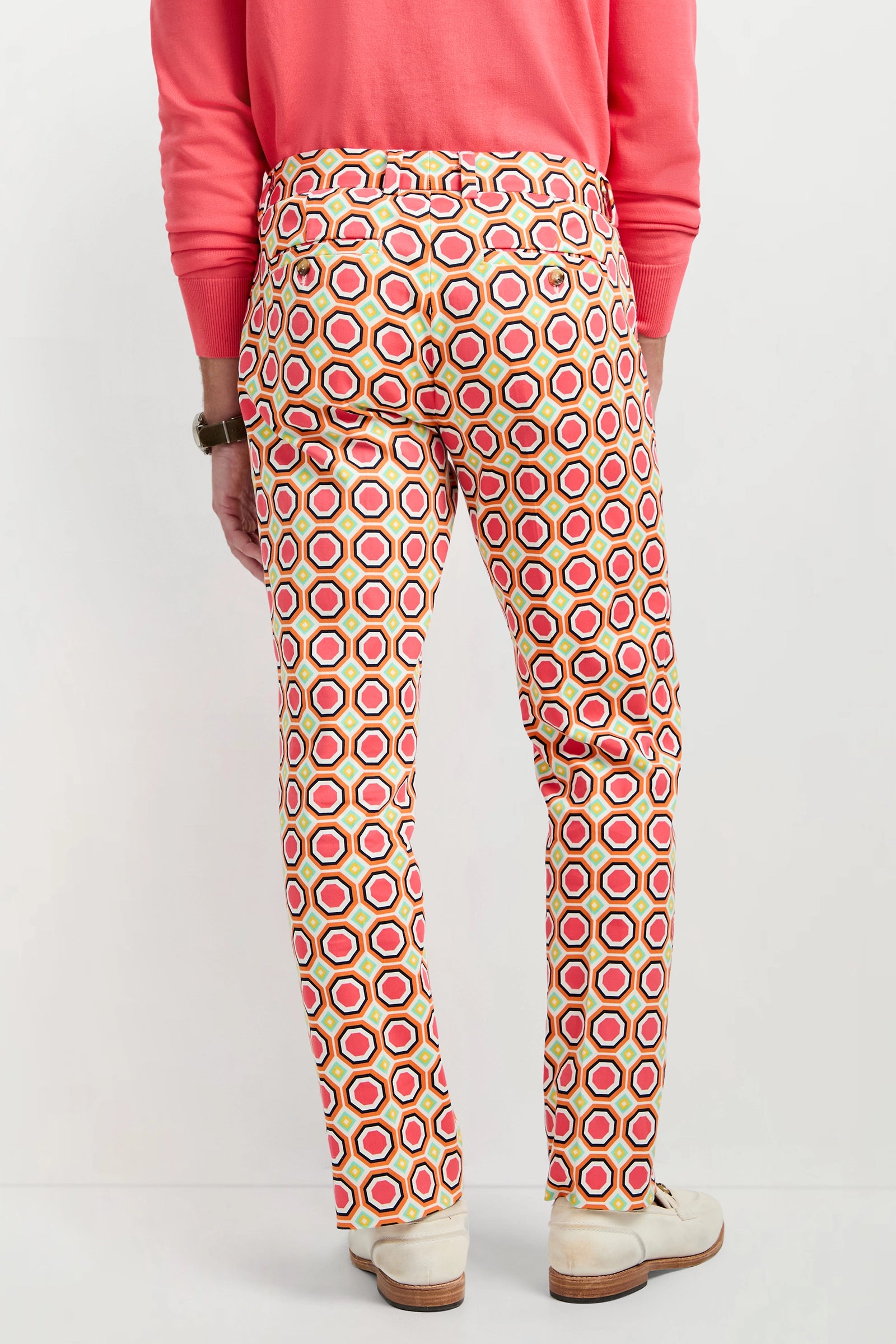 A person wearing white shoes, a pink sweater, and the Clyde Slim Trouser - Salerno Herringbone stands facing away from the camera against a plain background.