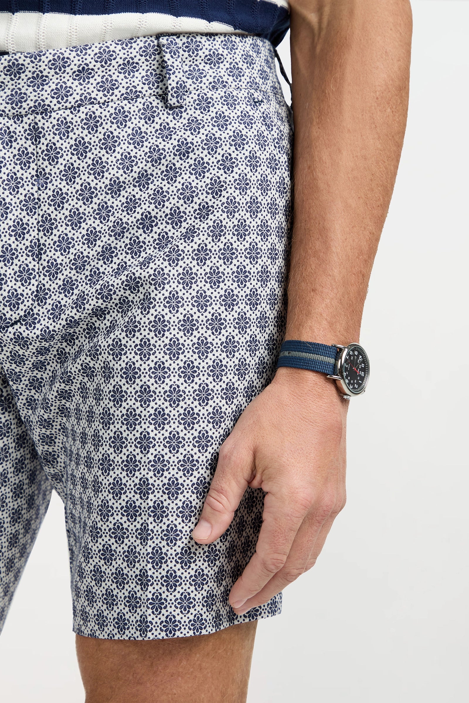 Wearing the Lawrence Short - Daisy Jacquard, a navy belt, and a navy watch with a blue strap, only the lower torso and right arm are visible against a plain background.