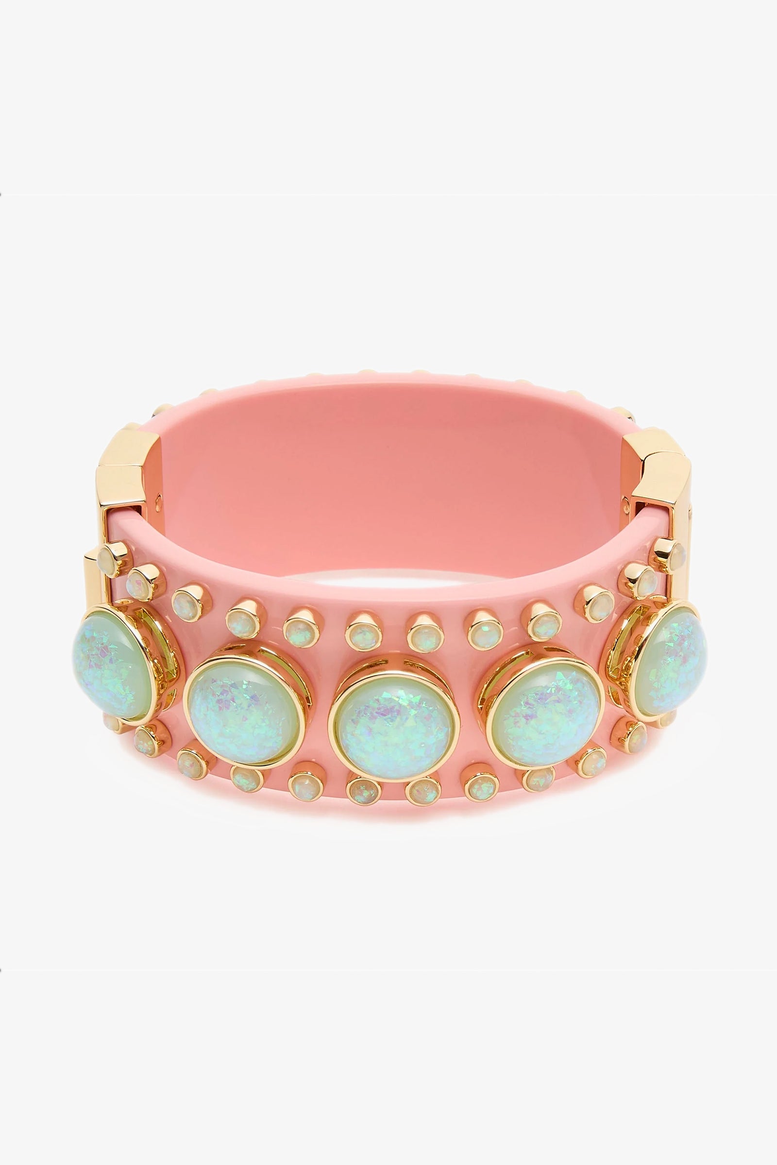 The Deco Hinged Cuff is a wide pink bracelet with gold accents, adorned with large iridescent opal-like stones and rows of small round studs around its surface.