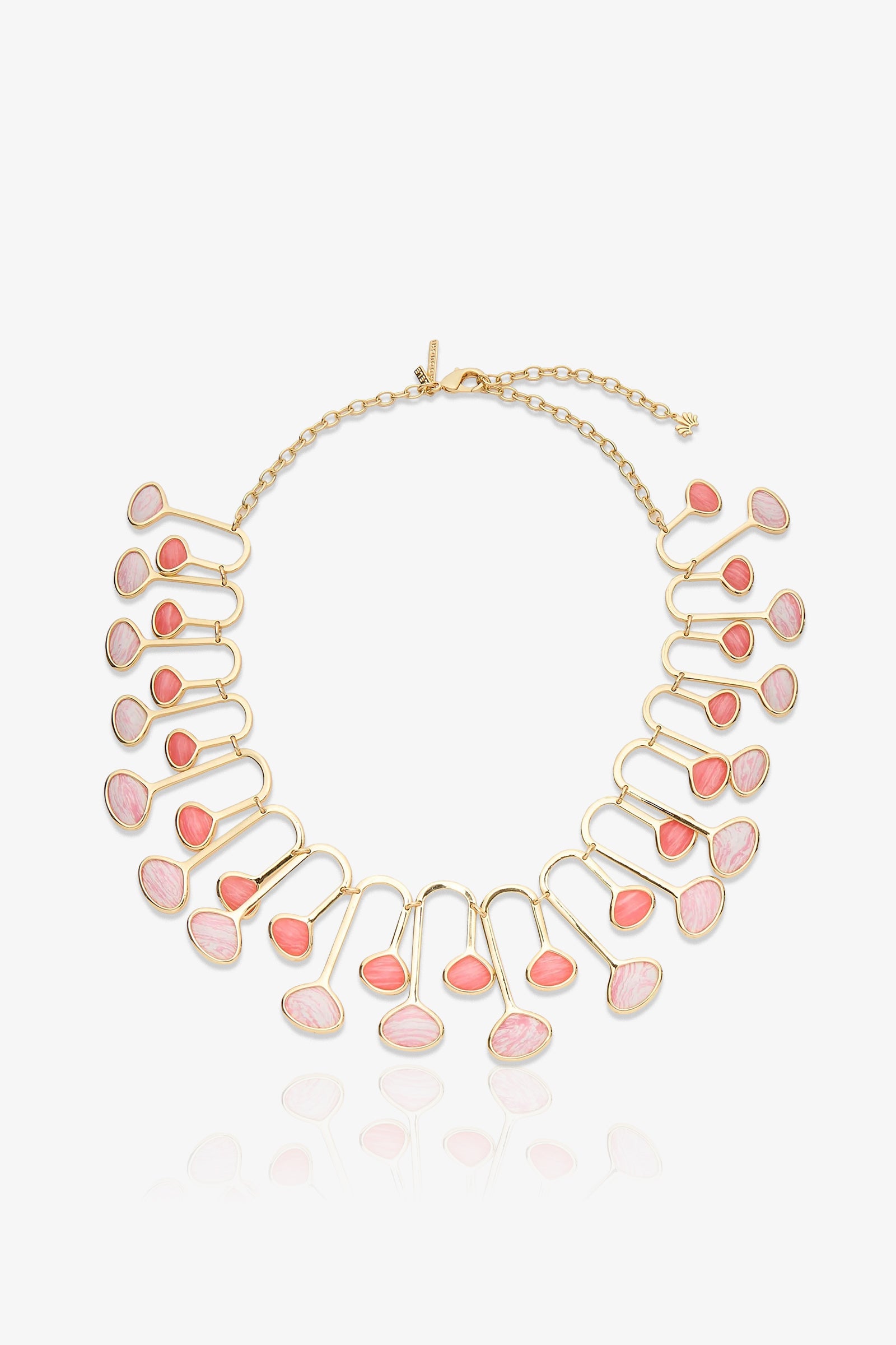 The Flamingo Necklace is a gold necklace with a chain clasp, featuring 22 pink and coral oval stones set in a fan-like pattern. The stones are arranged in pairs along curved gold frameworks, creating a bold, elegant statement piece.