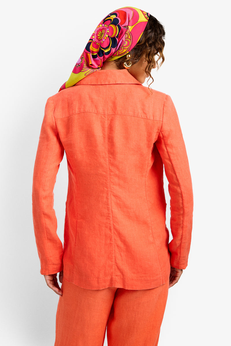 A person with curly hair is seen from behind wearing the Azurine Blazer and matching pants, paired with a vibrant headscarf featuring pink, yellow, and orange patterns.