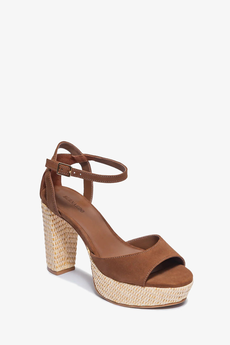The Valeria Platform Sandal features brown suede, an ankle strap with buckle, open toe, and a chunky high heel with a woven straw-textured heel and platform base.