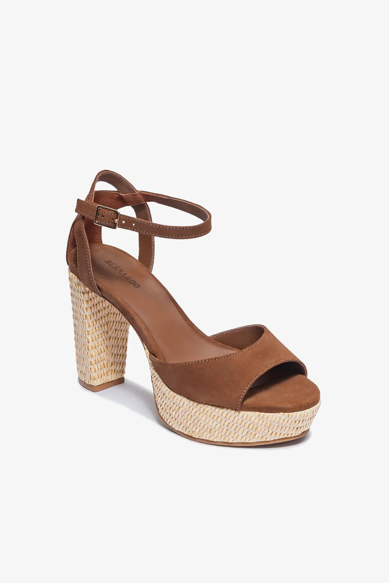 The Valeria Platform Sandal, crafted in brown suede with a chunky woven block heel, open toe, and an ankle strap featuring a buckle, is displayed against a plain white background.