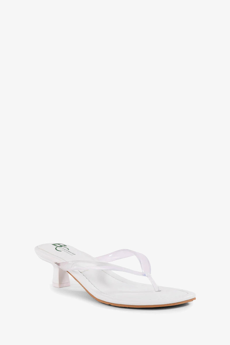 The Starbust Sandal in white features a thong design, heeled sole, and clear plastic straps, showcased at an angle on a plain white background.