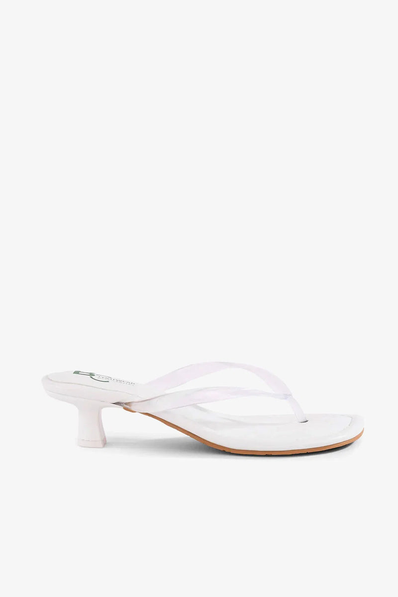 The Starbust Sandal, featuring a white thong strap design and a low, cylindrical heel, is displayed in a side view against a plain background.