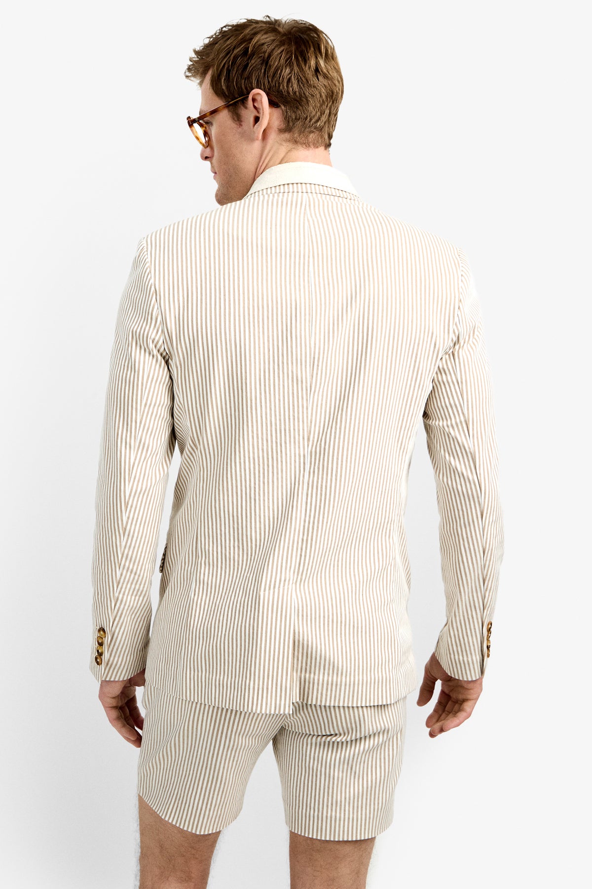 A man wearing glasses and the LOUIE BLAZER with matching shorts stands facing away from the camera against a plain white background.