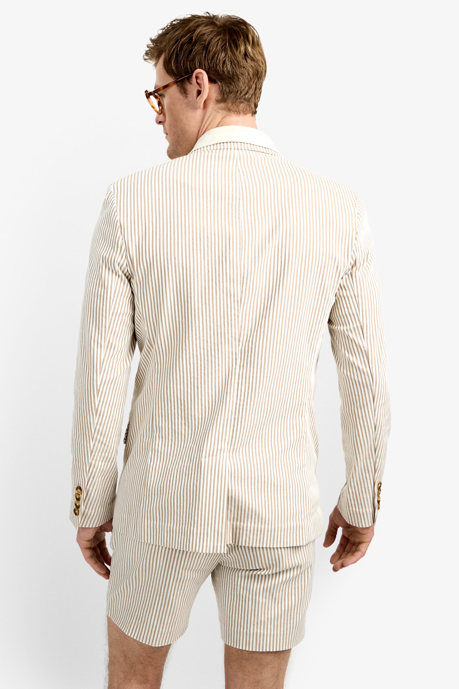 A man wearing glasses and the LOUIE BLAZER with matching shorts stands facing away from the camera against a plain white background.