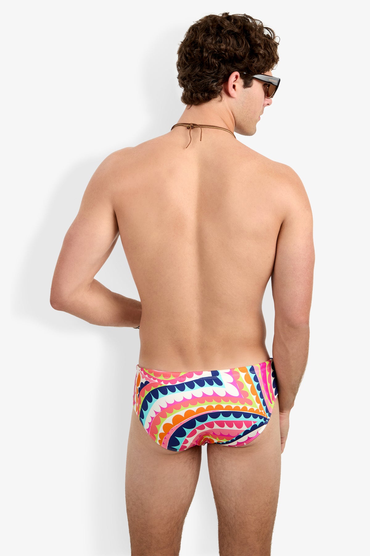 A man with short curly hair, wearing sunglasses and the Bondi Swim Brief, stands facing away against a plain white background.