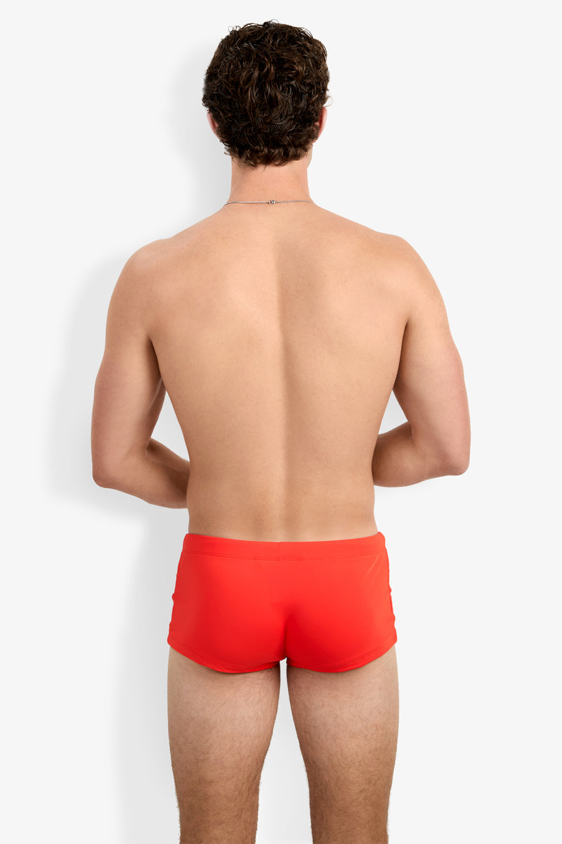 A man with short brown hair is seen from the back, standing against a plain white background and wearing the Montego Bay Swim Trunk in bright red.