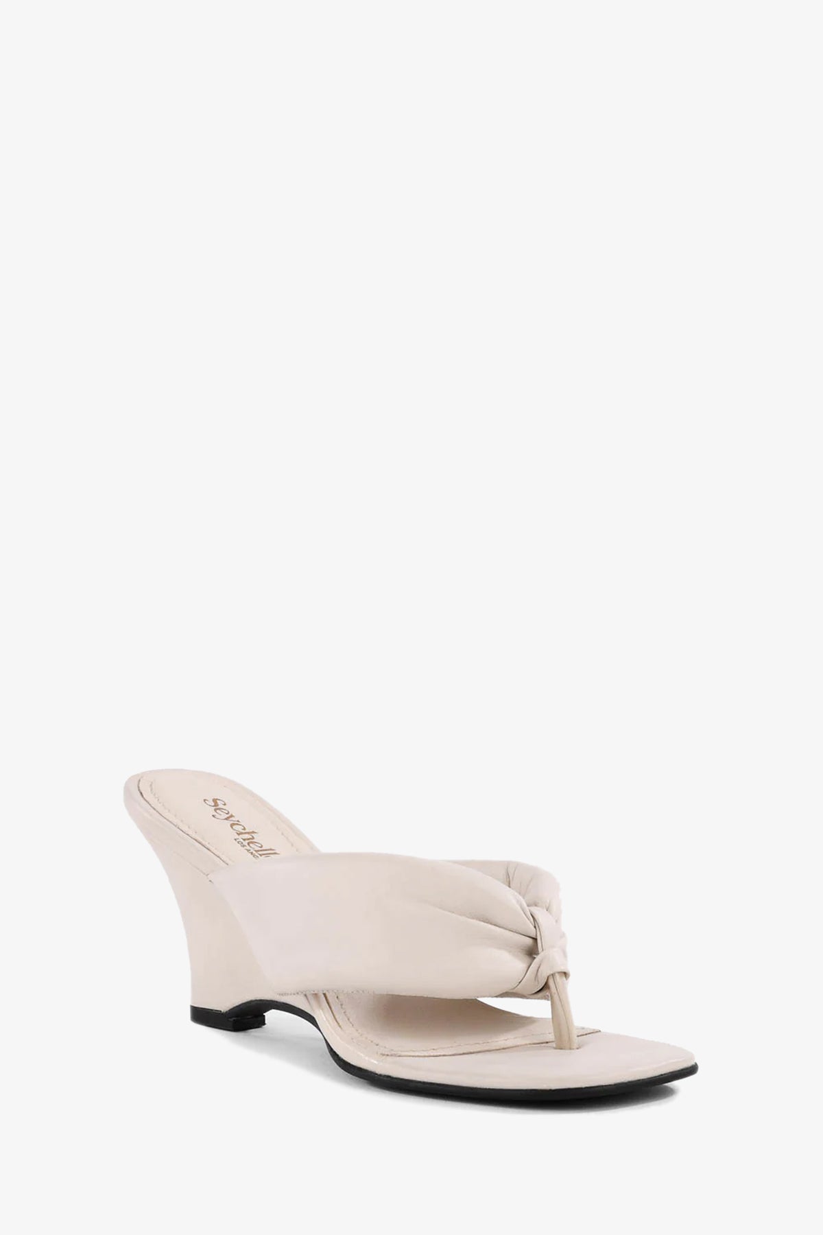 The Wishing Well Wedge is an off white sandal with a wedge heel, featuring a knotted thong strap and open toe, shown on a plain white background.
