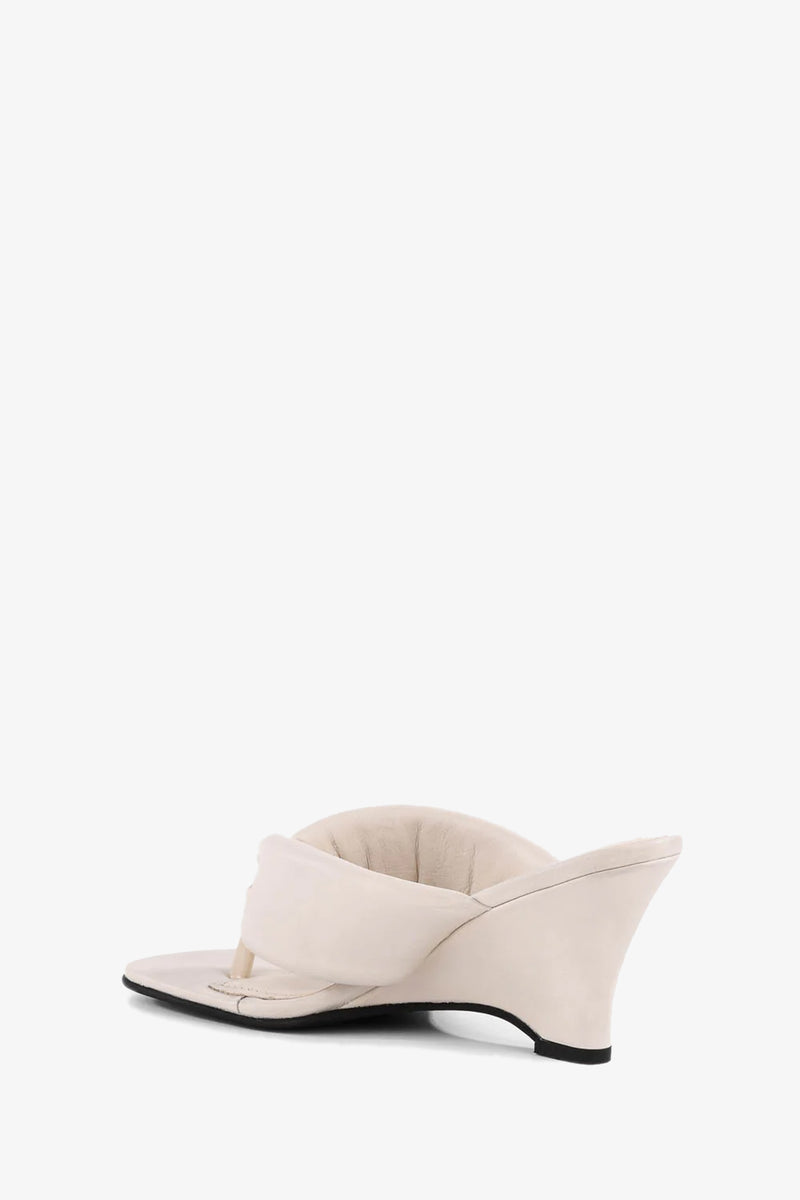 A side view of the Wishing Well Wedge, a single beige sandal with a cushioned footbed and padded thong strap, shown against a plain white background.