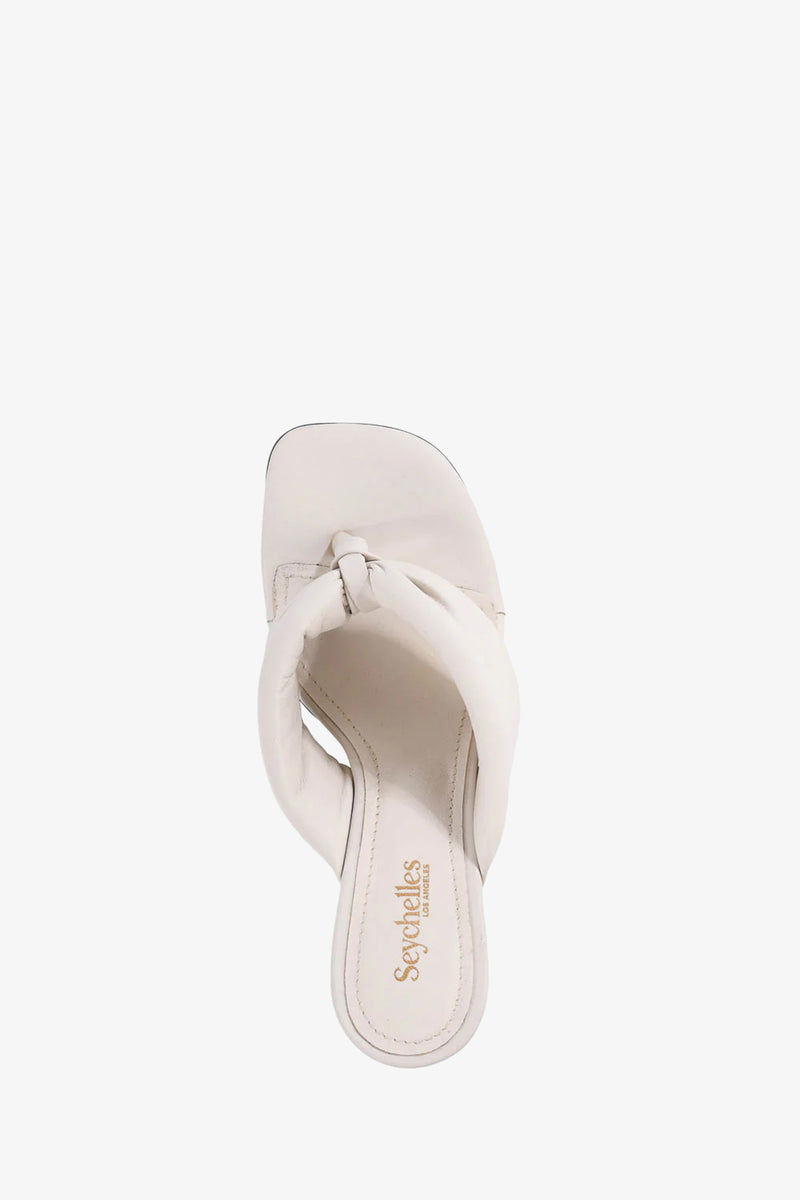 Top view of the Wishing Well Wedge, a white slip-on sandal with a thick twisted strap and square toe. The insole displays the Seychelles logo in gold lettering.