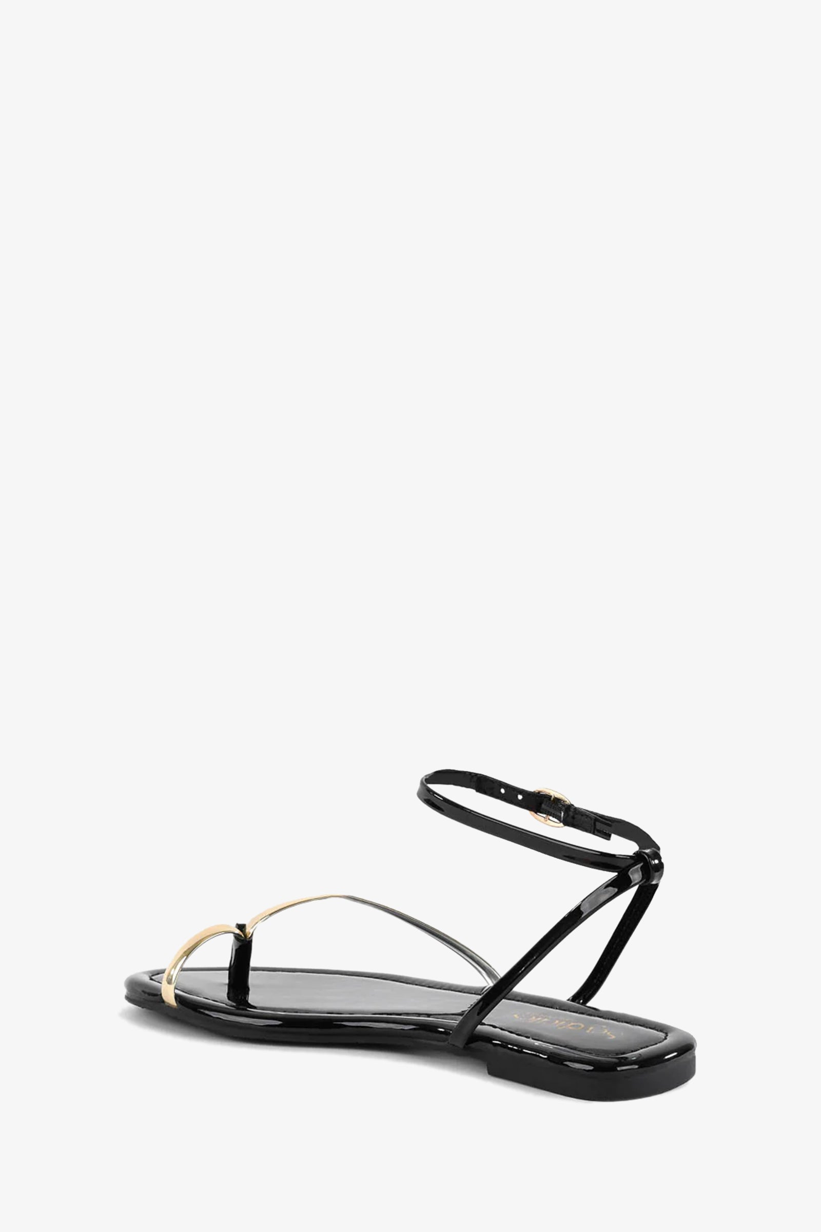 The A Little Extra Sandal features black patent thong styling with thin gold and black straps, plus an ankle strap finished with a gold buckle.