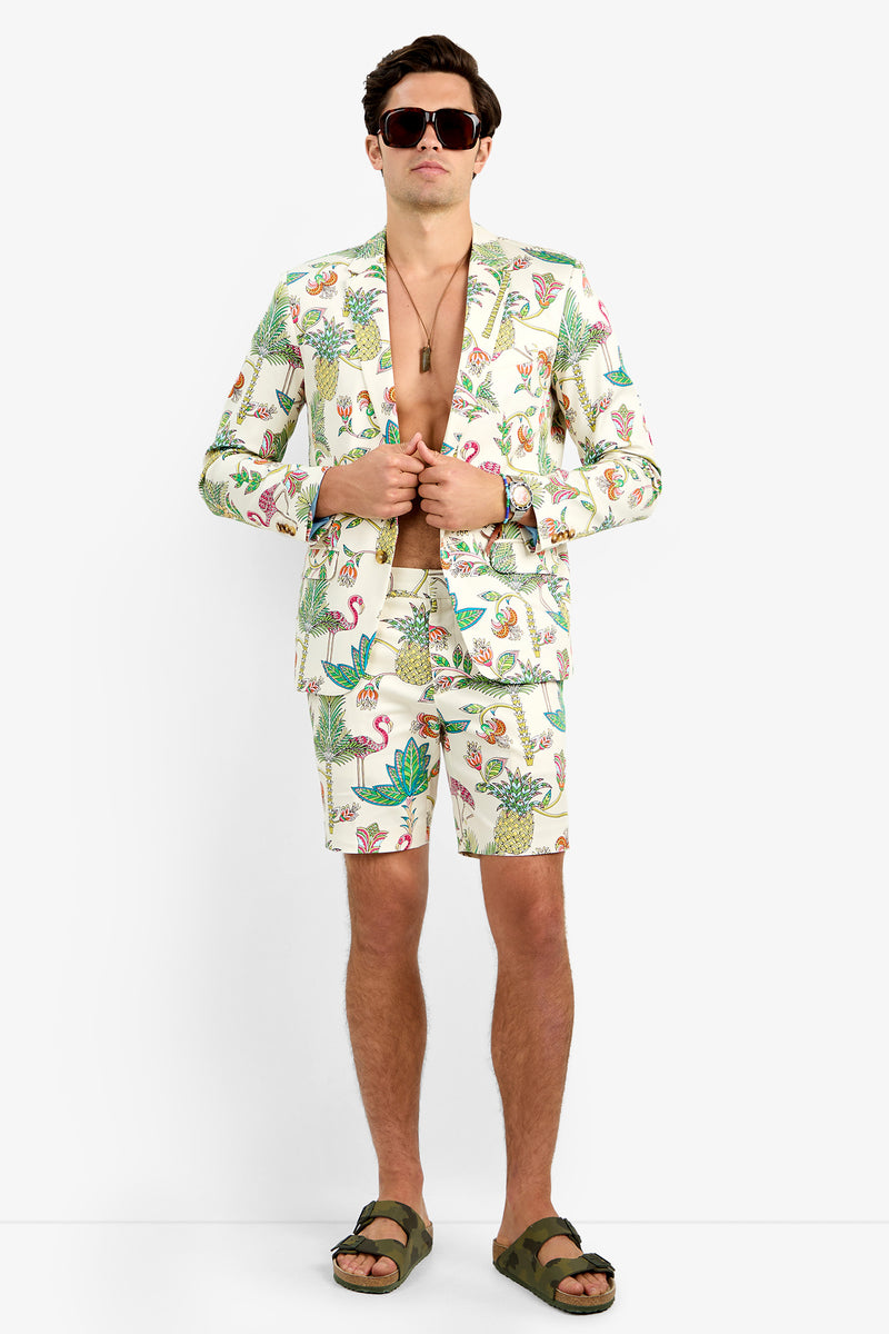 A man wearing sunglasses, the MULTI THURSTON BLAZER with matching shorts, green sandals, and a necklace stands confidently against a plain white background.