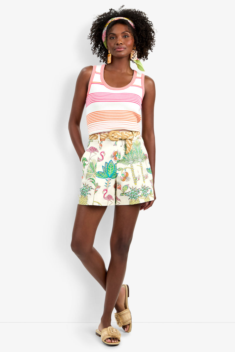 A woman wearing a striped tank top, the Noriah Short with tropical print and rope belt, gold sandals, hoop earrings, and a colorful headband stands against a white background.
