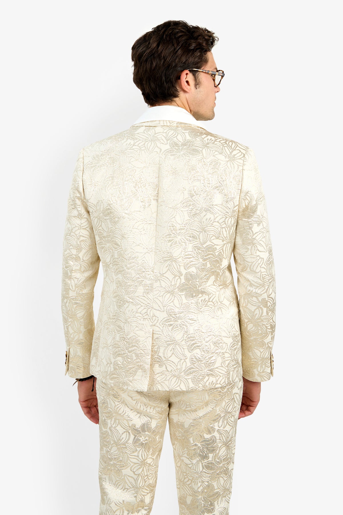 A man stands facing away from the camera against a plain white background, wearing glasses and the cream-colored Thurston Blazer, which features a subtle floral pattern.