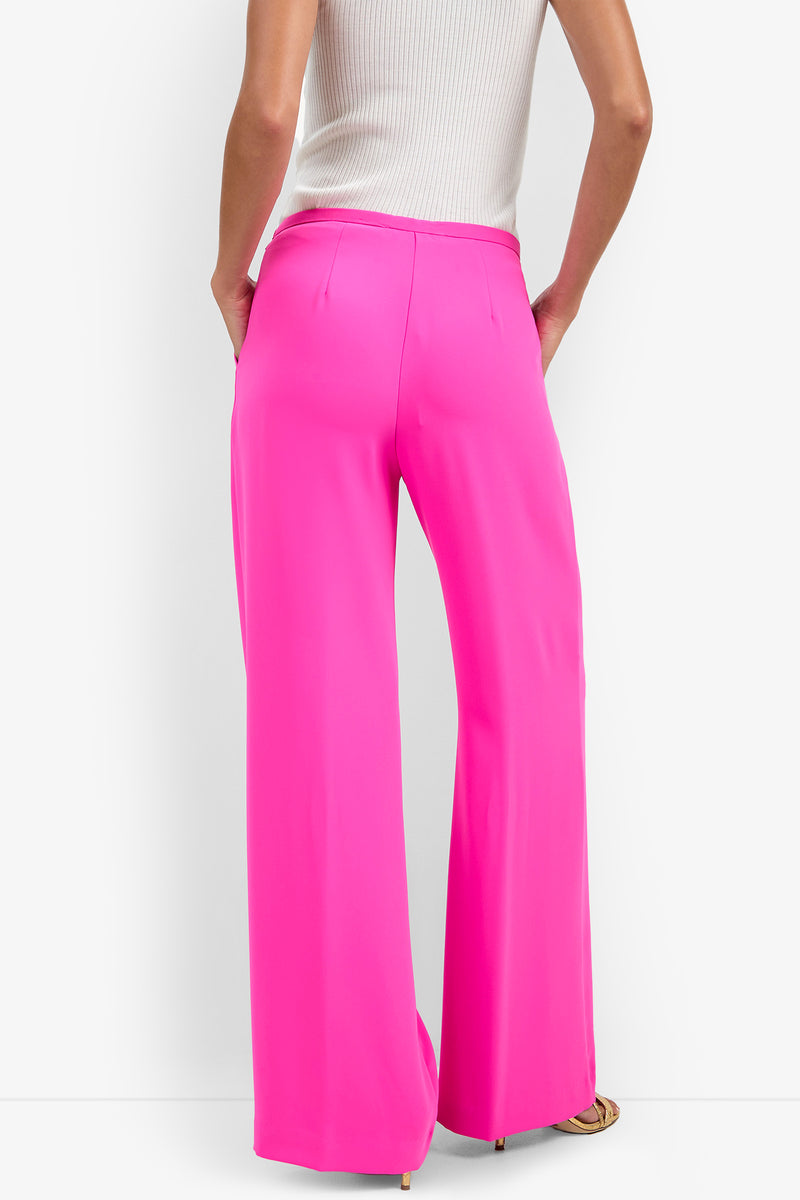 A person is seen from the back wearing the sleeveless white ribbed Lyndi Top paired with bright pink wide-leg trousers, standing against a white background.