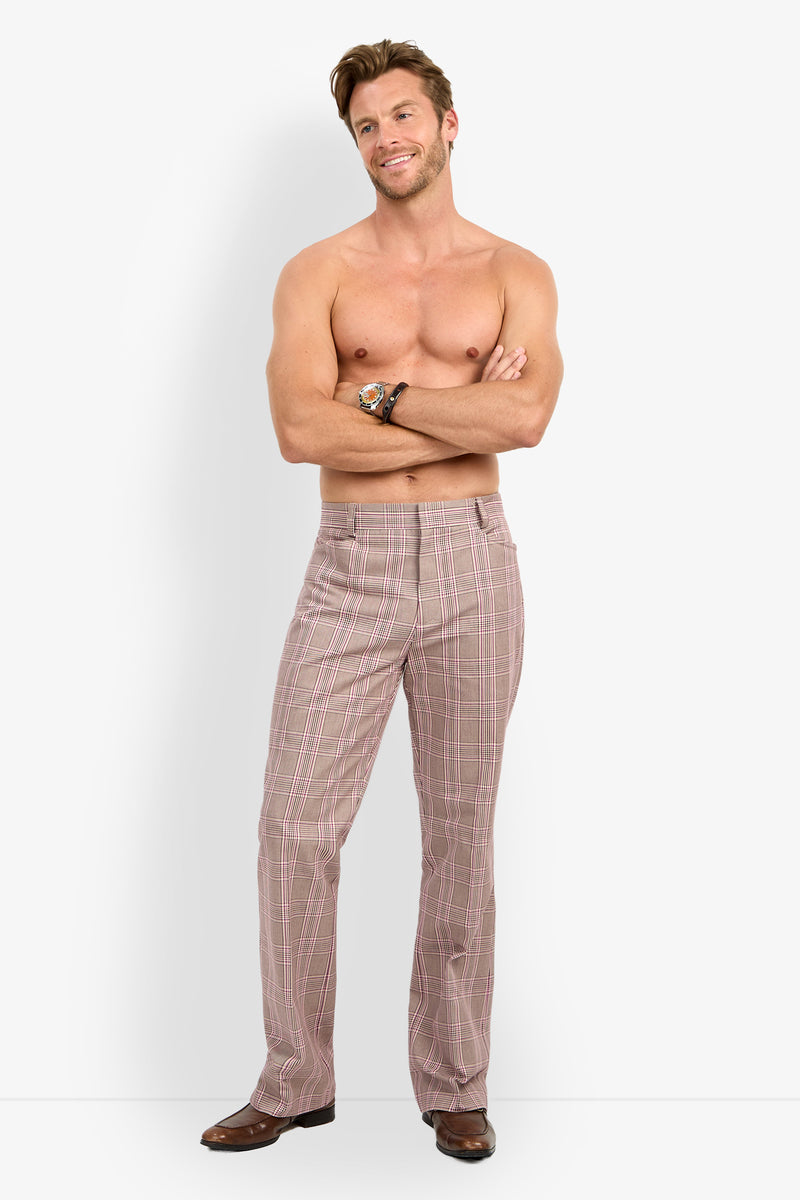 A smiling, shirtless man stands with arms crossed, wearing the ALEJANDRO BOOTLEG TROUSER and brown shoes against a plain white background.