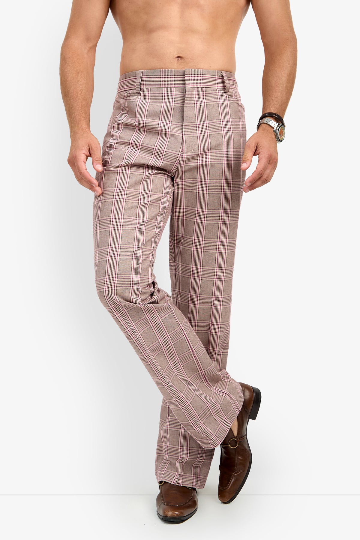 A shirtless man stands against a white background, wearing ALEJANDRO BOOTLEG TROUSER brown plaid dress pants and brown dress shoes, with one leg crossed in front of the other and a hand on his hip.
