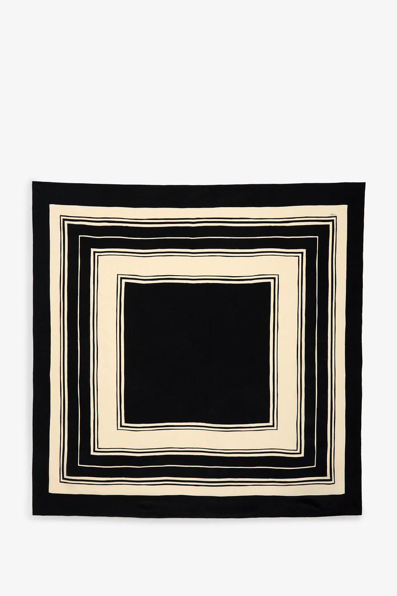 The Scala Silk Scarf features a square design with black and cream concentric rectangles forming a striking geometric border. Its center is black, bordered by cream and slim black lines, all set against a crisp white background.