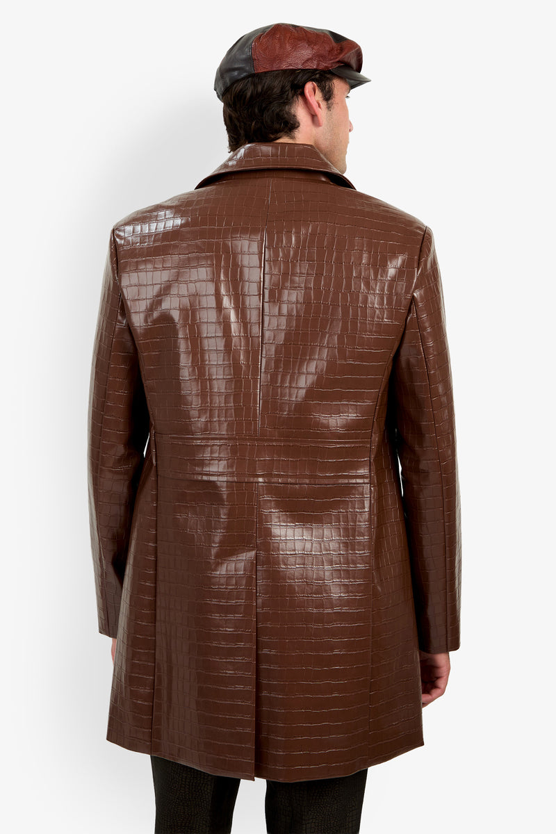 A person wearing the Morton Trench Coat, featuring a shiny brown crocodile-pattern texture, along with a matching brown cap, shown from the back against a plain white background.