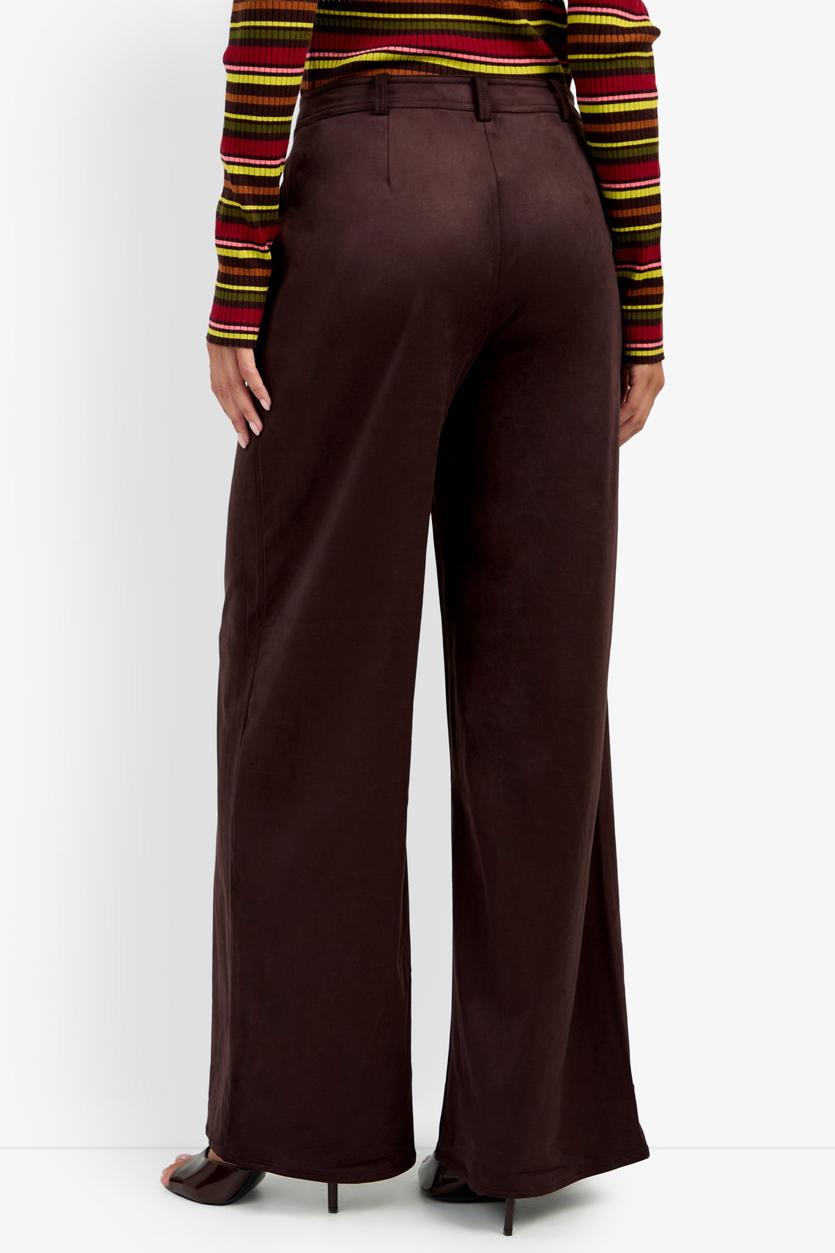 Someone wearing the Zinn Pant, a pair of wide-leg, high-waisted brown pants, paired with a striped long-sleeve top and standing with their back to the camera against a white background.