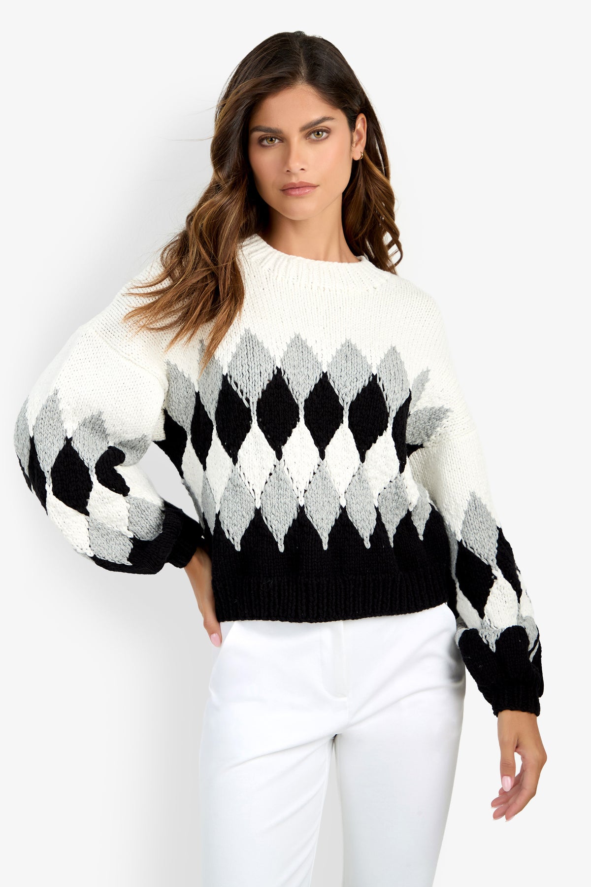 A woman wears a Cavallari Sweater featuring a white, black, and grey argyle-patterned long-sleeve design.