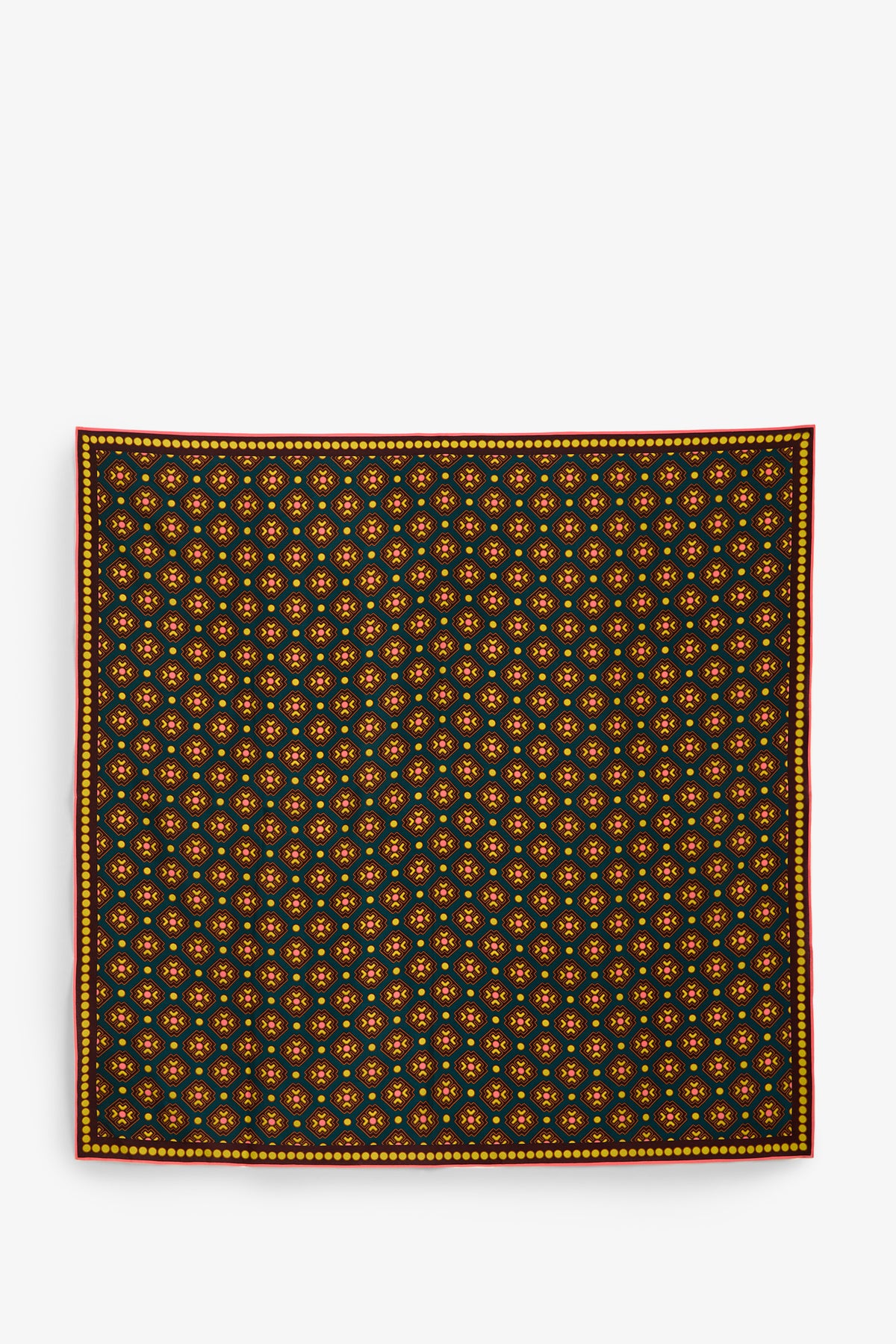 The FOULARD FRINGE SCARF features a symmetrical, evenly spaced repeating floral pattern in yellow and orange on a dark background, finished with a thin red and yellow border along the edge.