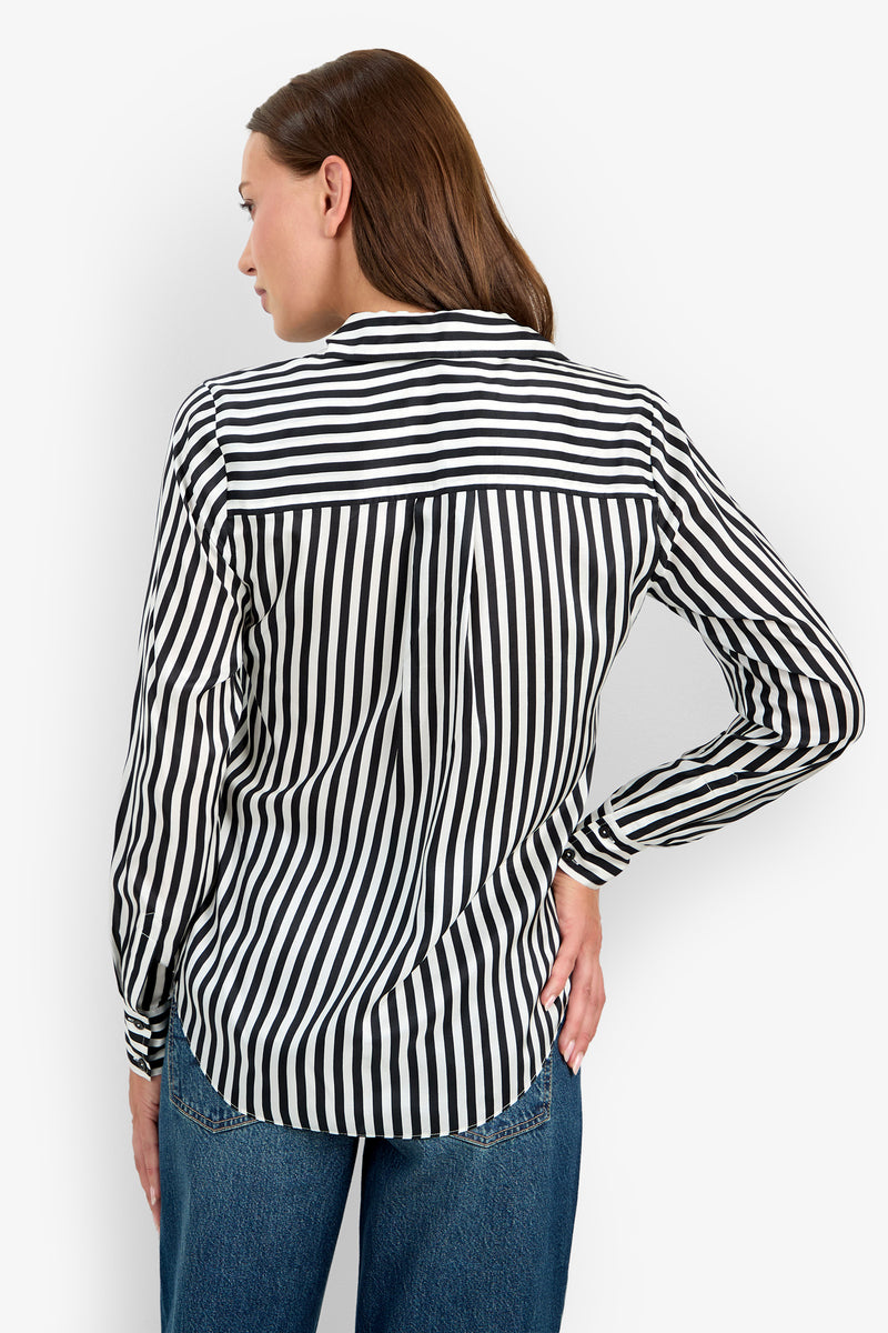 A woman with brown hair is pictured from the back, standing with one hand on her hip, wearing blue jeans and the Rouge Top—a black and white vertically striped long-sleeve shirt.