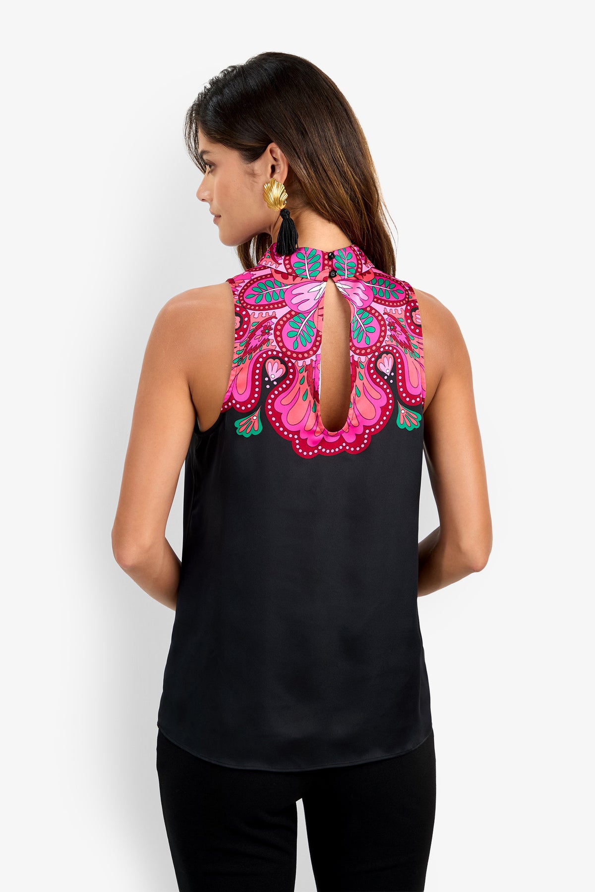 A woman with long hair and gold earrings is seen from behind, wearing the Loveage Top—a sleeveless black piece featuring a keyhole back and vibrant pink, red, and blue embroidery along the upper back and neckline.