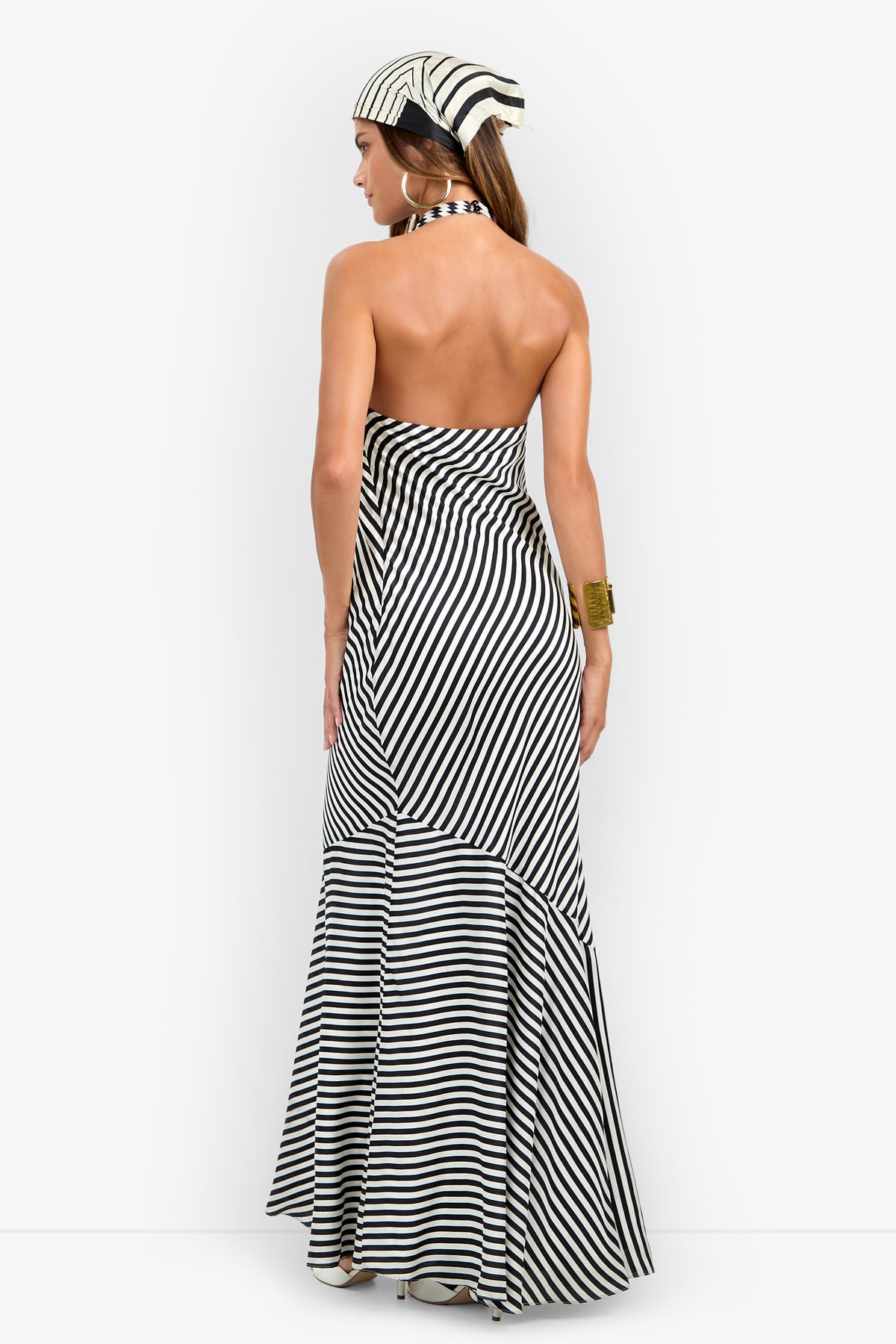 A woman models the Lady Dress, a black and white striped halter-neck design with a matching headscarf, posing with her back to the camera against a plain white background.