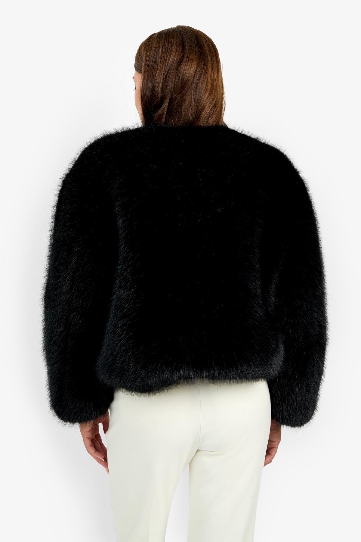 A person with brown hair, shown from the back, is wearing the Avenn Jacket and white pants against a plain white background.